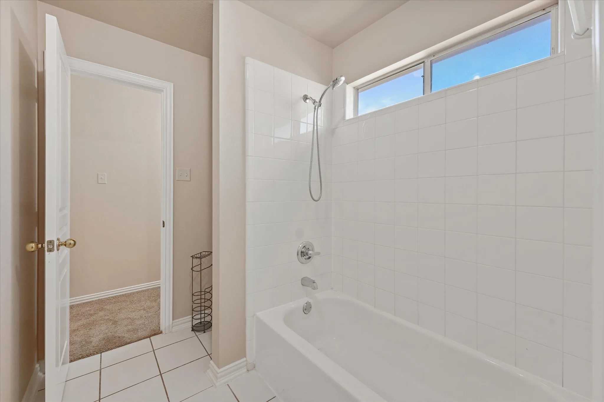 White tiled shower and tub combination with chrome fixtures