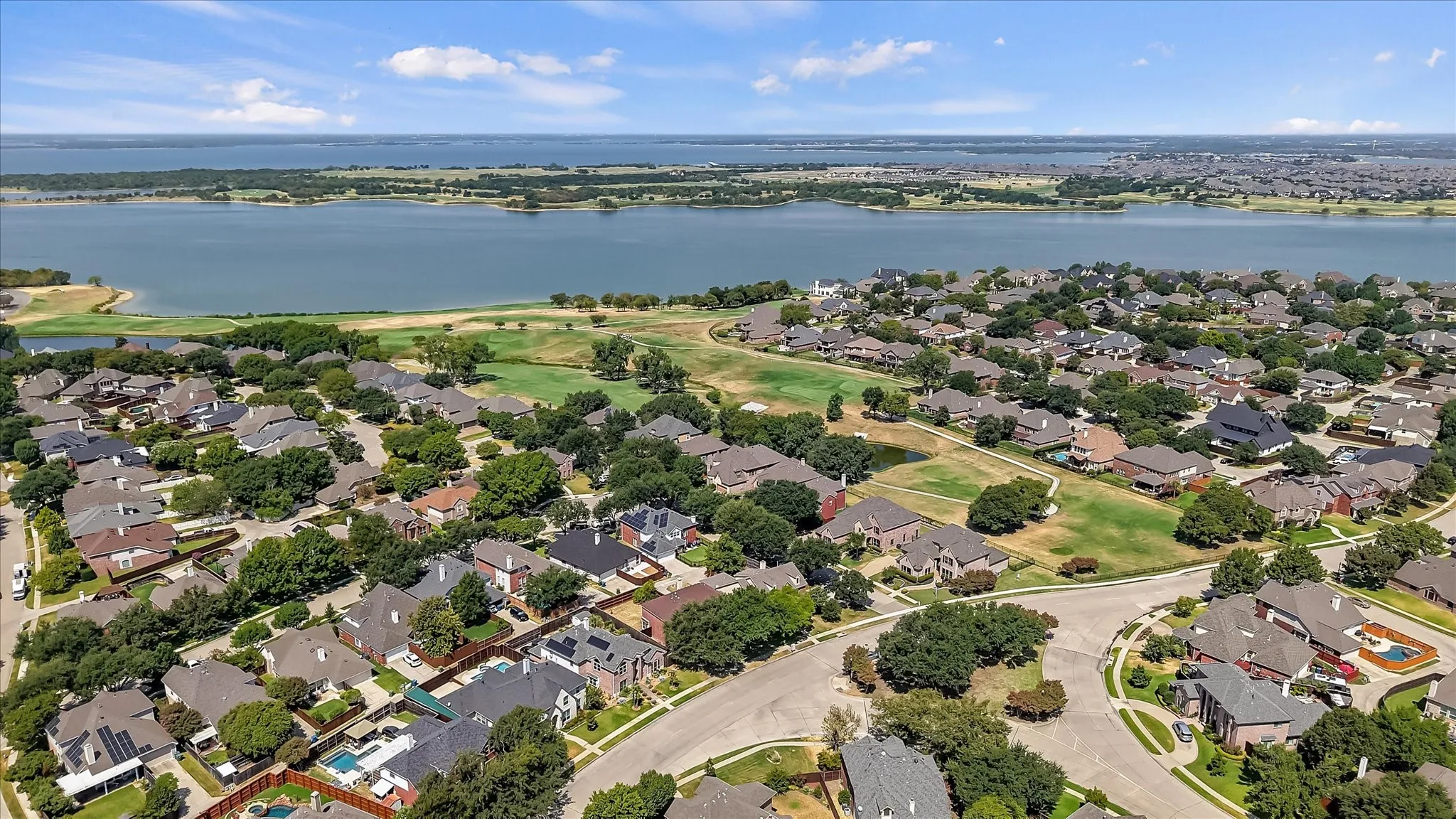 Residential neighborhood with a prominent lakefront, mature landscaping, and curved roadways