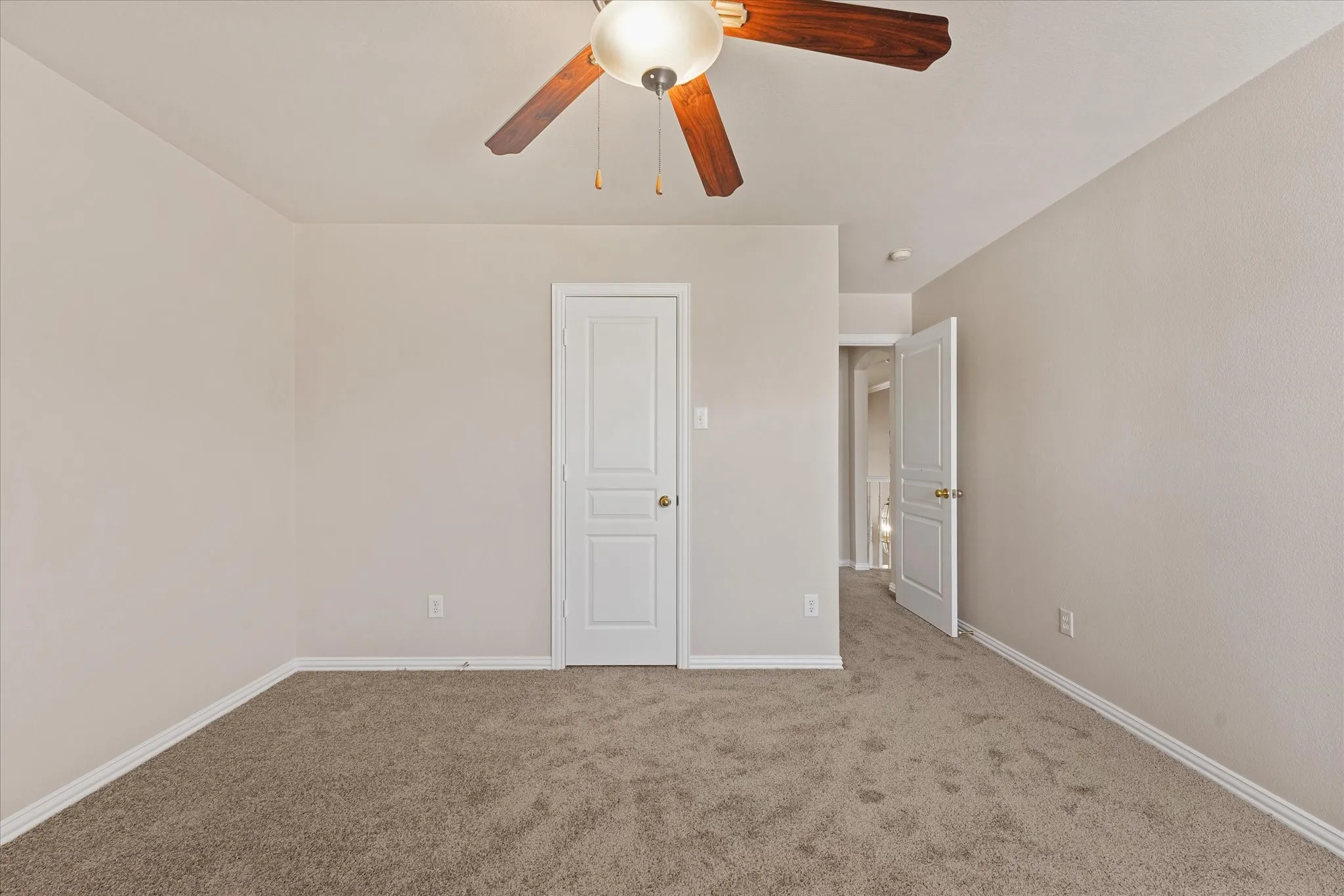 Neutral wall paint, plush carpeting, white interior doors, and a ceiling fan with light fixture