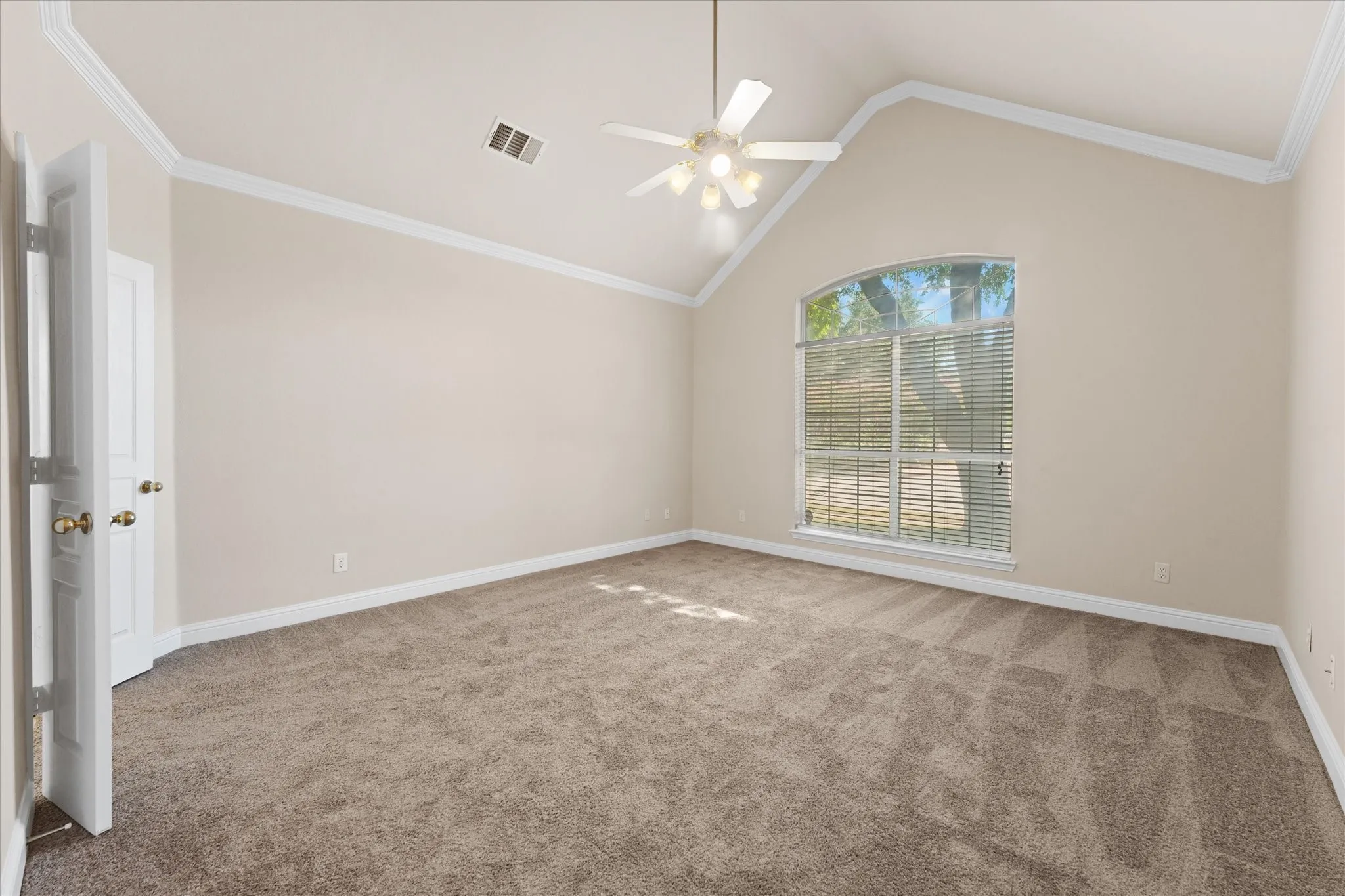 Vaulted ceiling with a ceiling fan, arched window with horizontal blinds, neutral wall paint, and light brown carpet