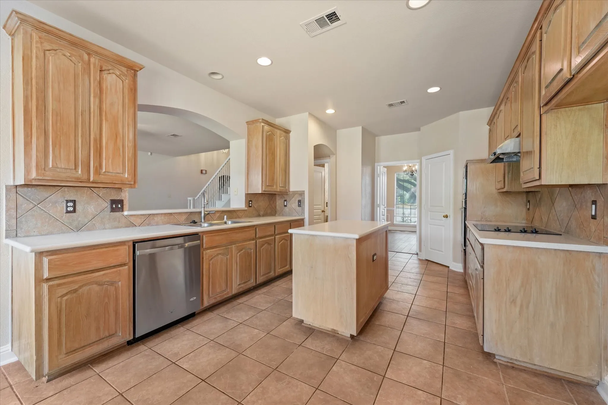 Kitchen featuring a central island, tile flooring, wood cabinetry, built-in stainless steel dishwasher, and recessed lighting