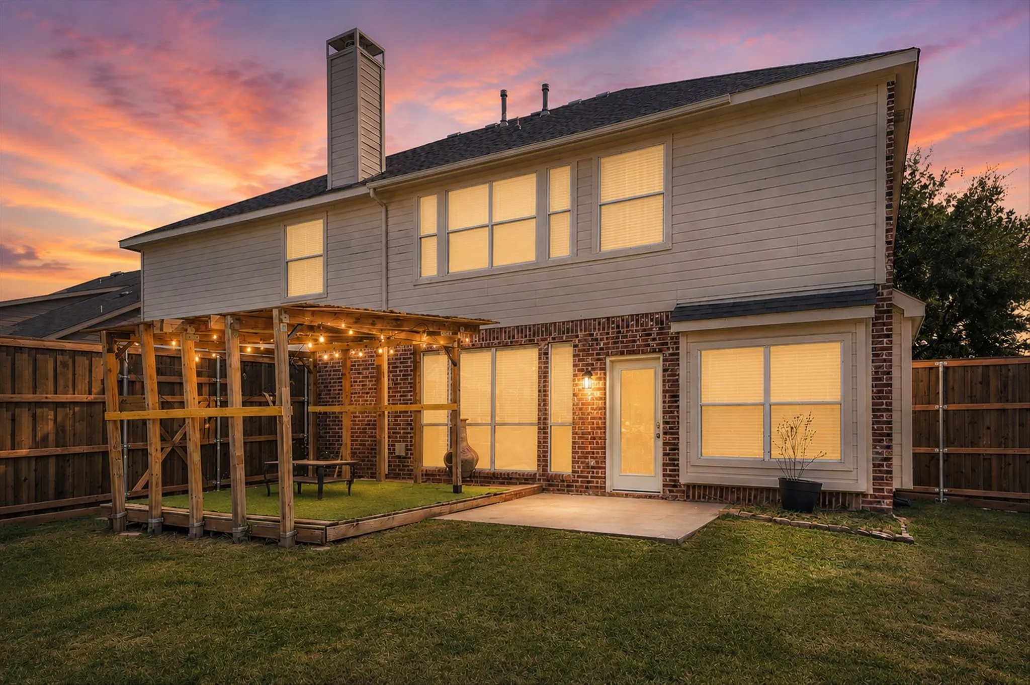 Expansive backyard featuring a pergola with string lights, a grass lawn, a paved patio, and a privacy fence