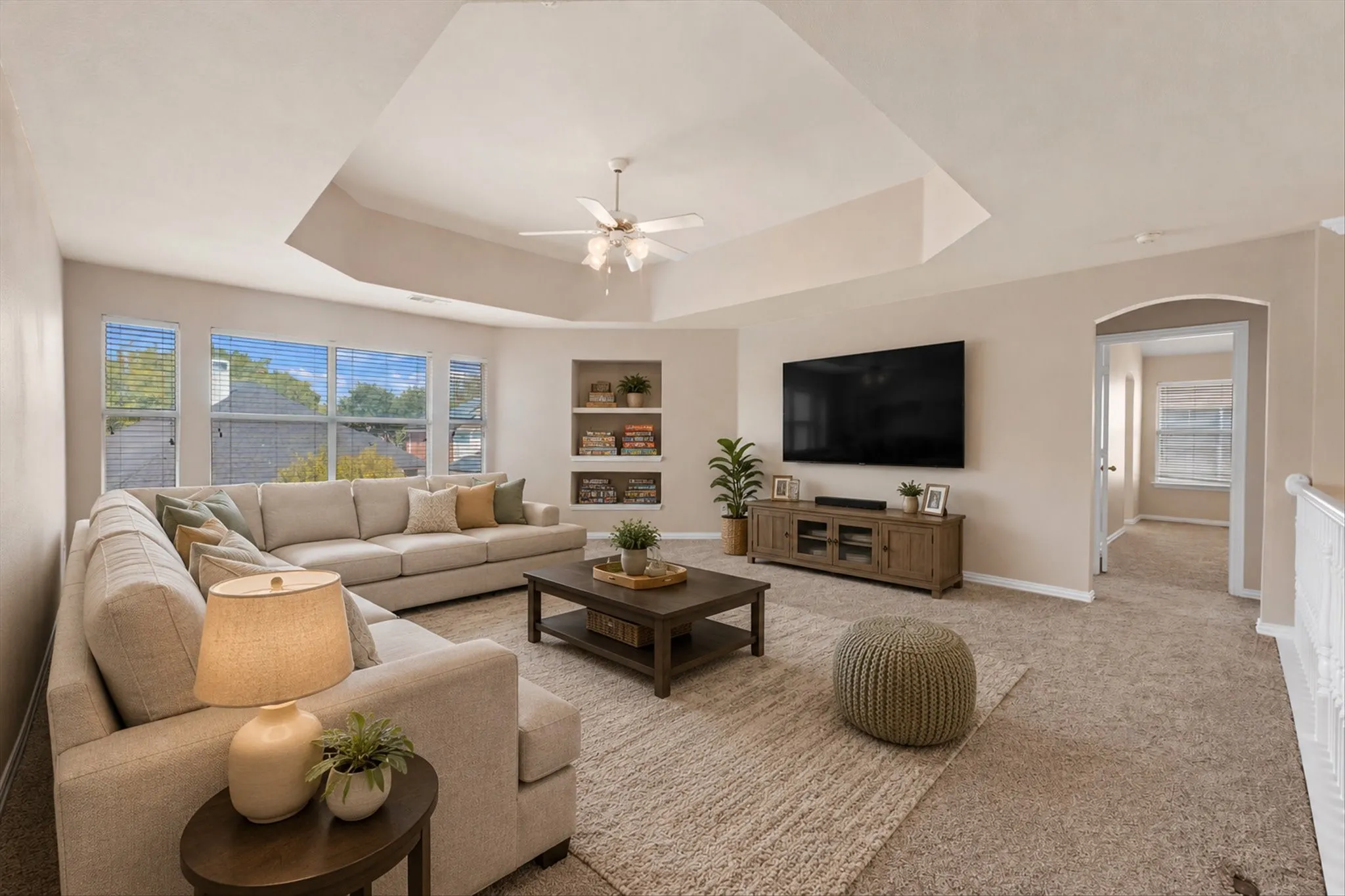 Virtual Stage..Tray ceiling with ceiling fan, built-in shelving, carpet flooring, and an arched doorway