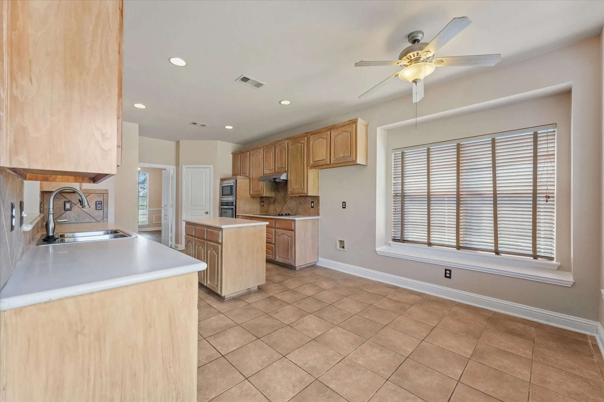 Kitchen featuring light wood cabinetry, a central island, tile flooring, and recessed lighting