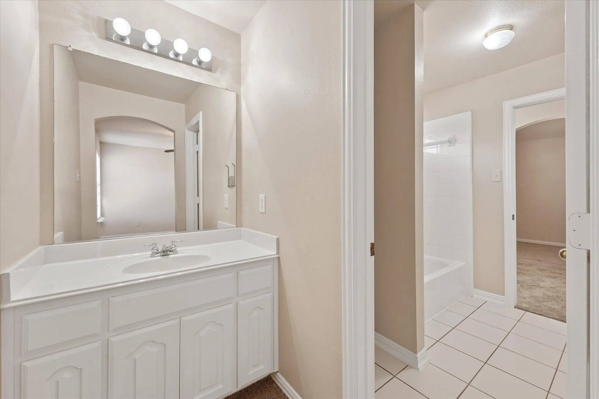 Single vanity with integrated sink, white cabinetry, and wall-mounted light fixture