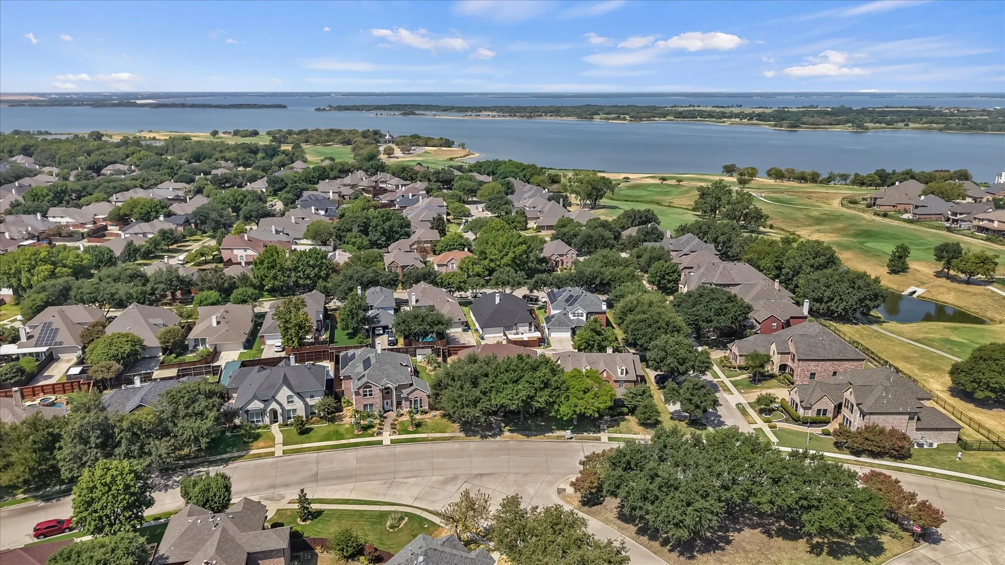 Expansive residential neighborhood with mature trees, a golf course, and a large body of water