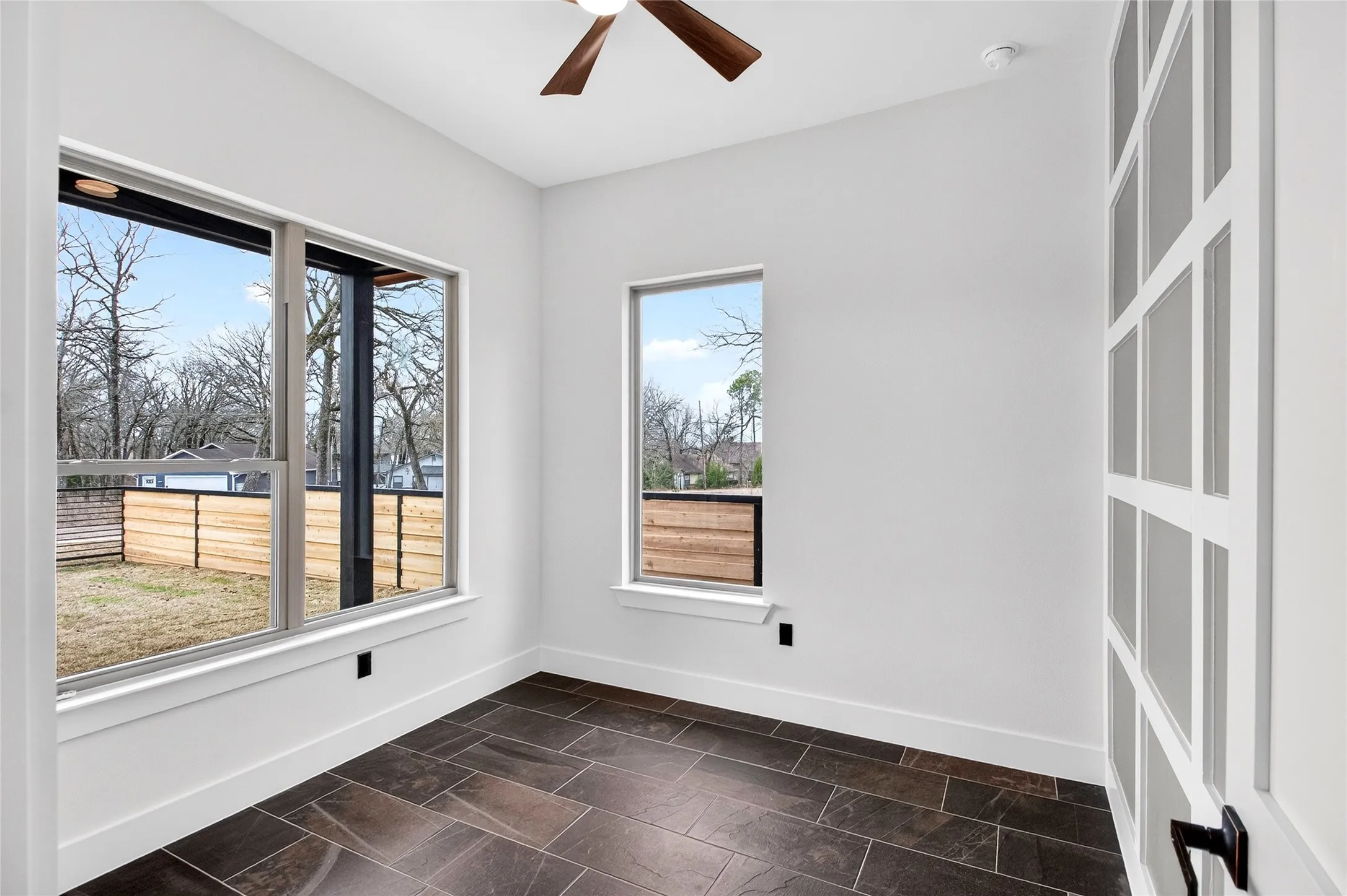 Spare room featuring a ceiling fan and dark stone finish flooring