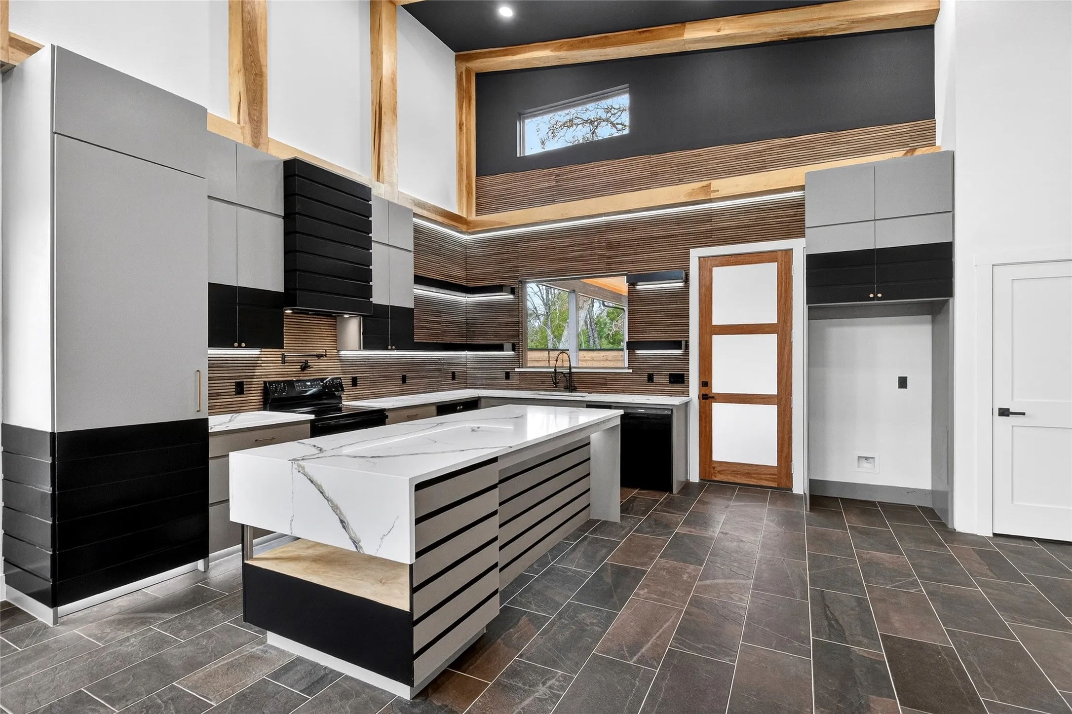 Kitchen featuring modern cabinets, light stone counters, a kitchen island, dual tone cabinetry, and a high ceiling