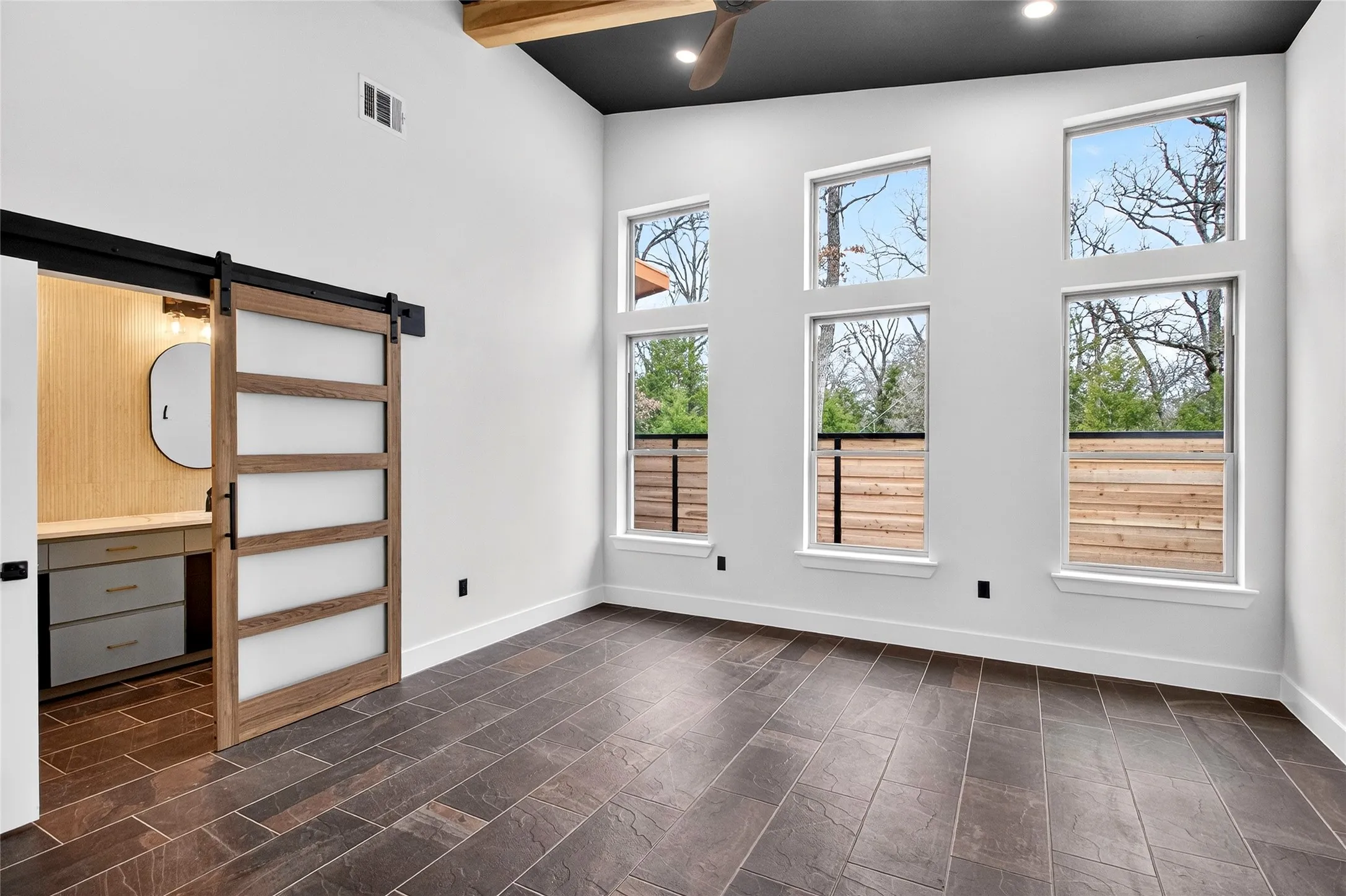 Empty room featuring a barn door, a ceiling fan, recessed lighting, and lofted ceiling