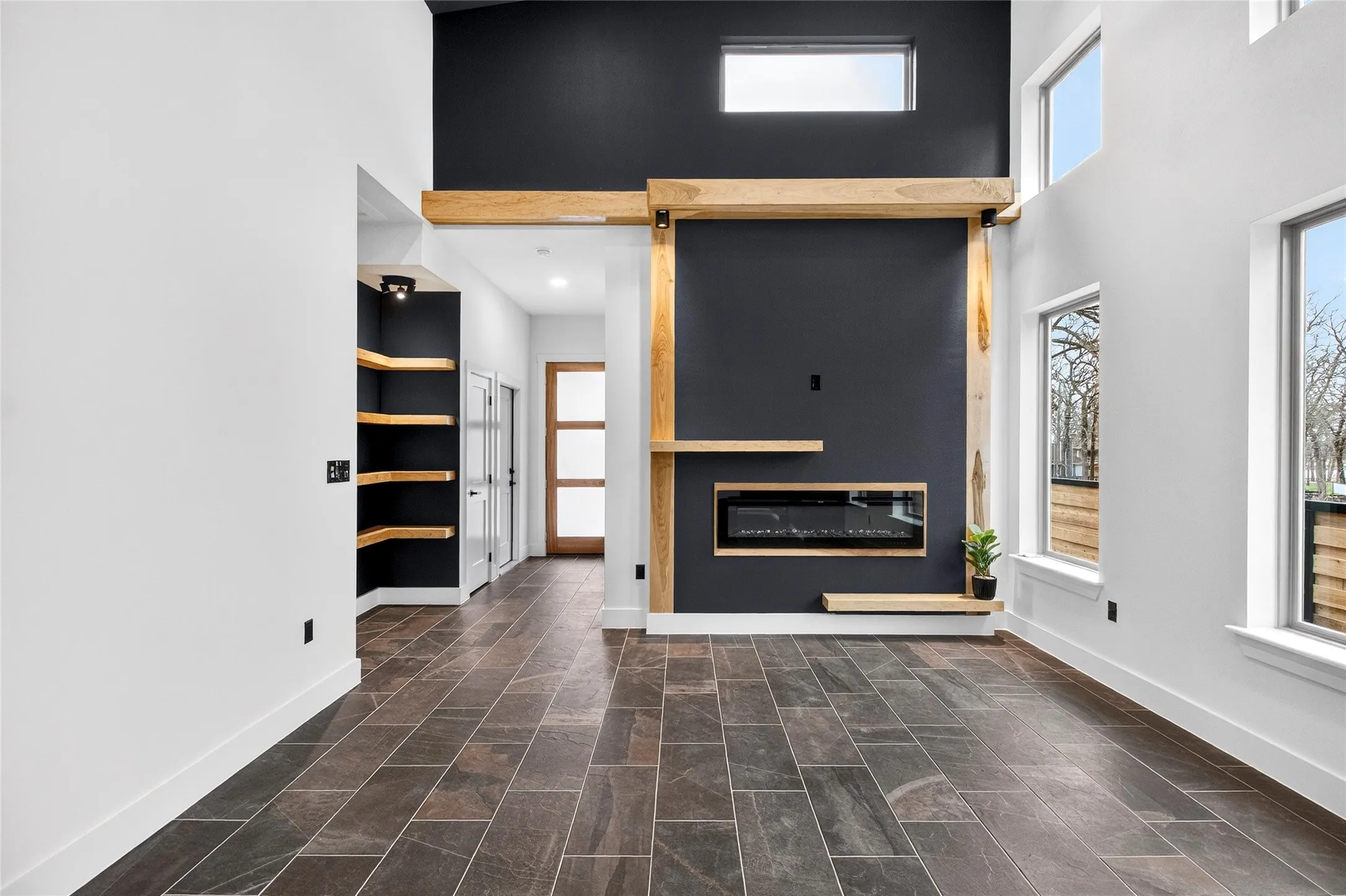 Unfurnished living room with a glass covered fireplace and a high ceiling