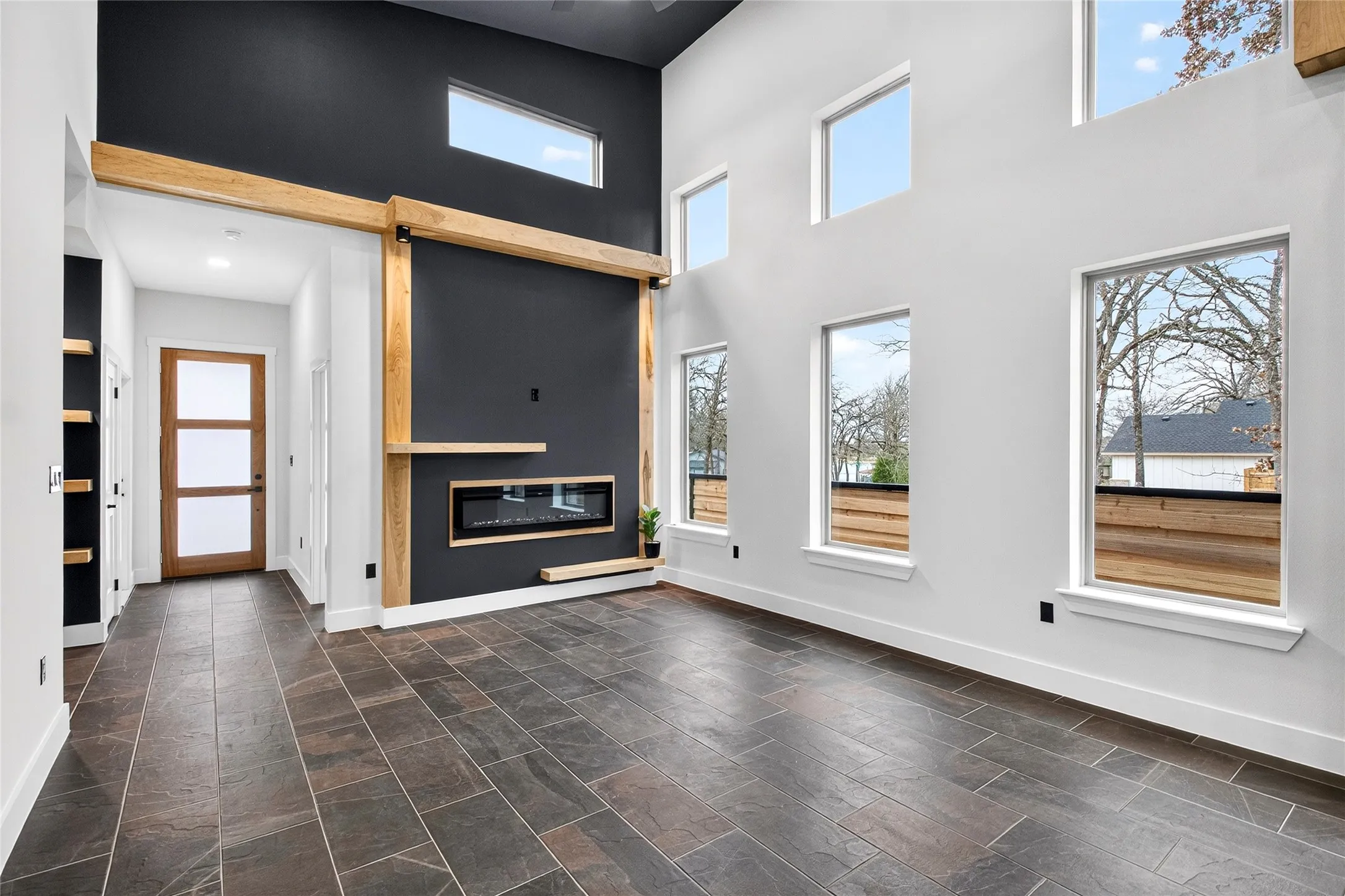 Unfurnished living room featuring a high ceiling and a glass covered fireplace