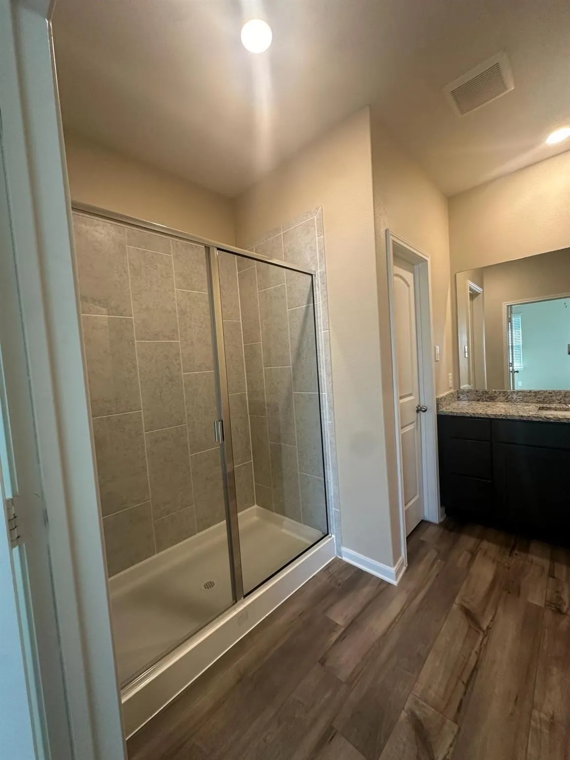 Walk-in shower with clear glass enclosure and tile surround