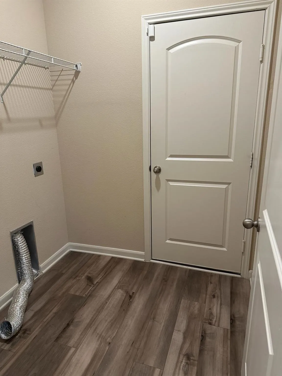 Utility space featuring wood-finish flooring, light tan walls, and white trim