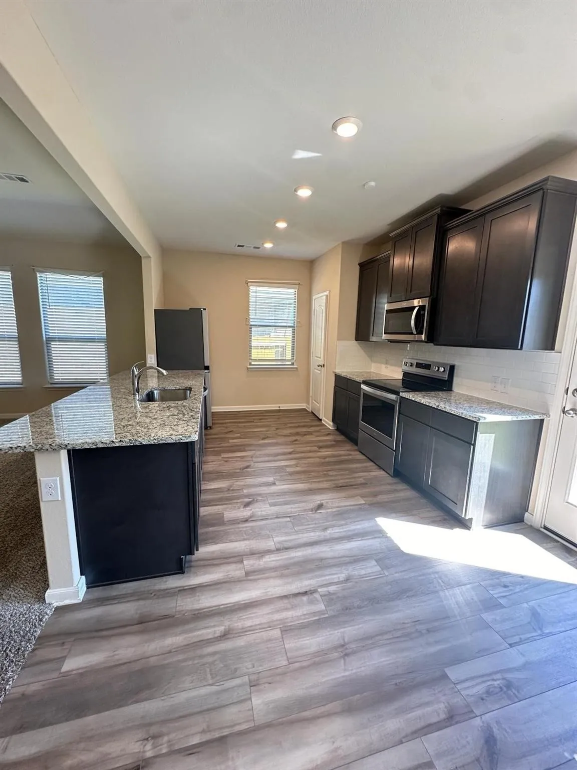 Modern kitchen featuring wood-finish flooring, dark cabinetry, and light-toned countertops