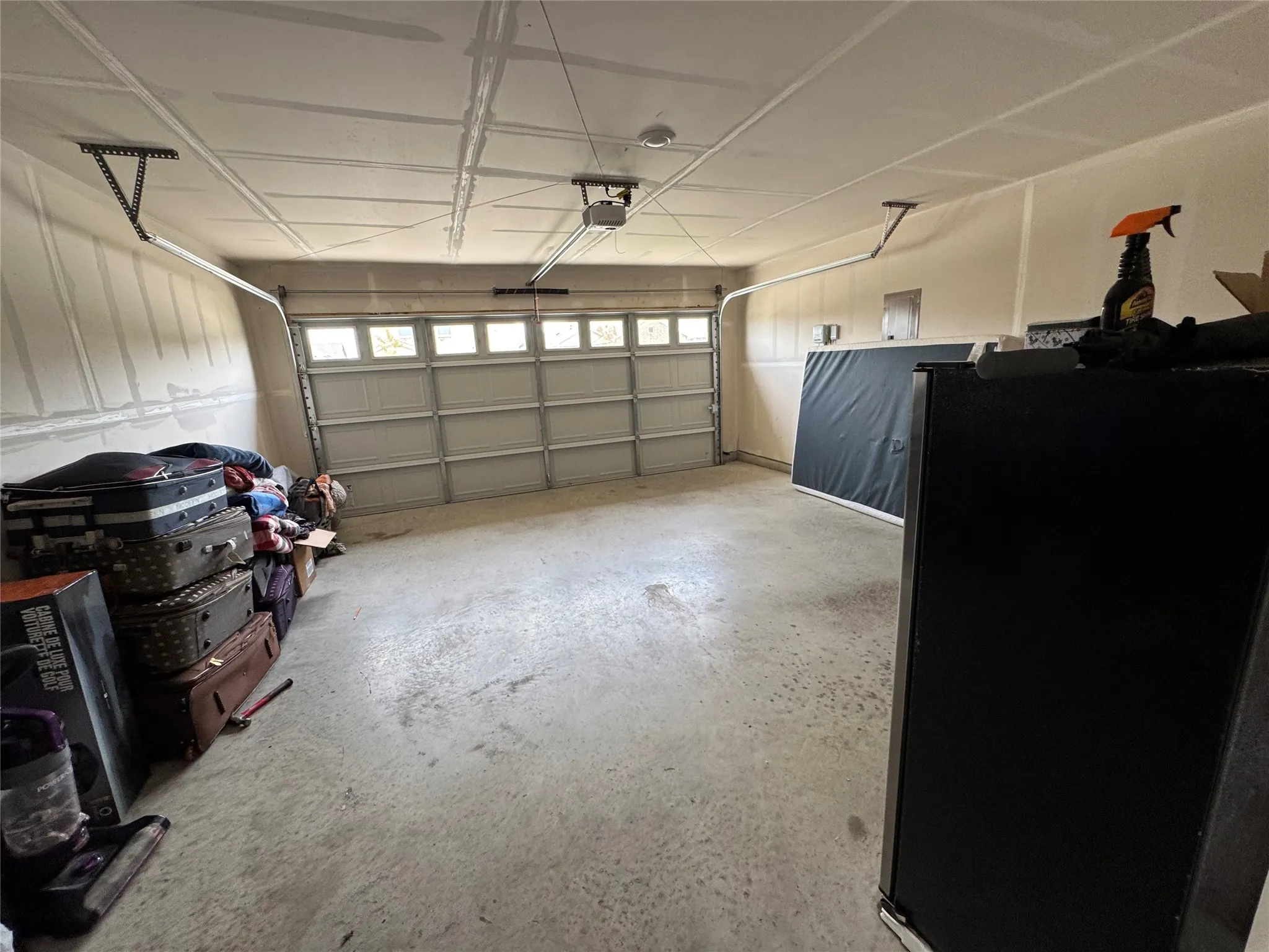Spacious two-car garage featuring a sectional garage door with upper window panels and an automatic opener