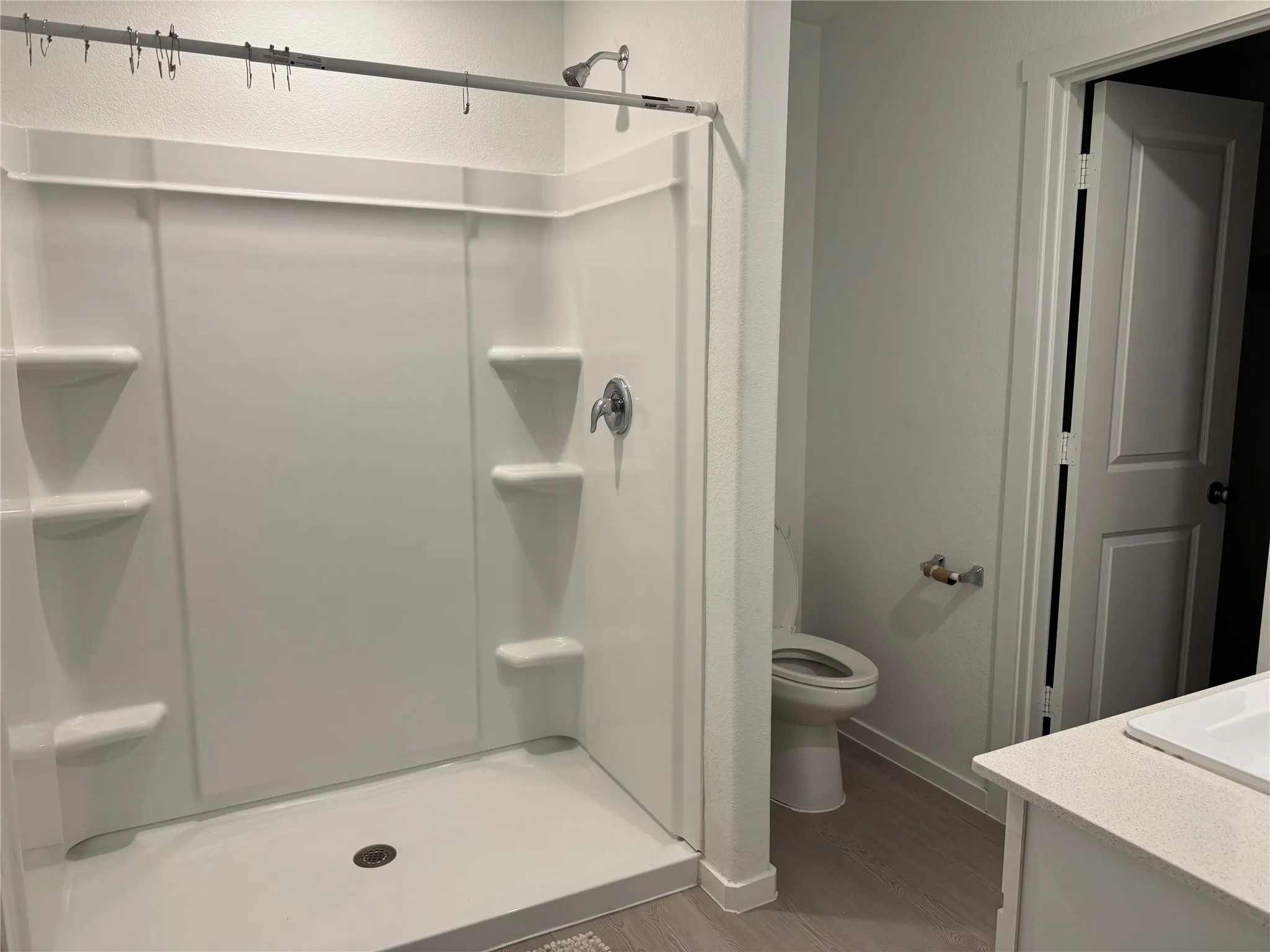 White shower stall with integrated shelving and chrome fixtures