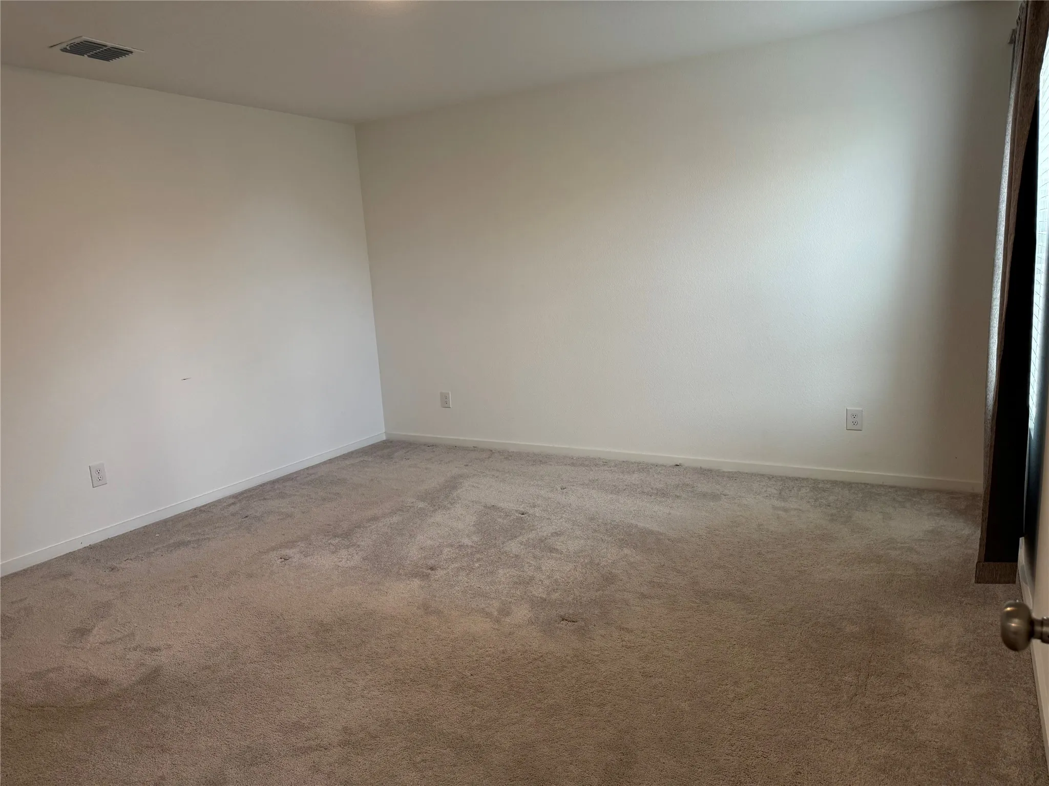 Spacious room featuring neutral carpeting, white wall finishes, and white baseboards