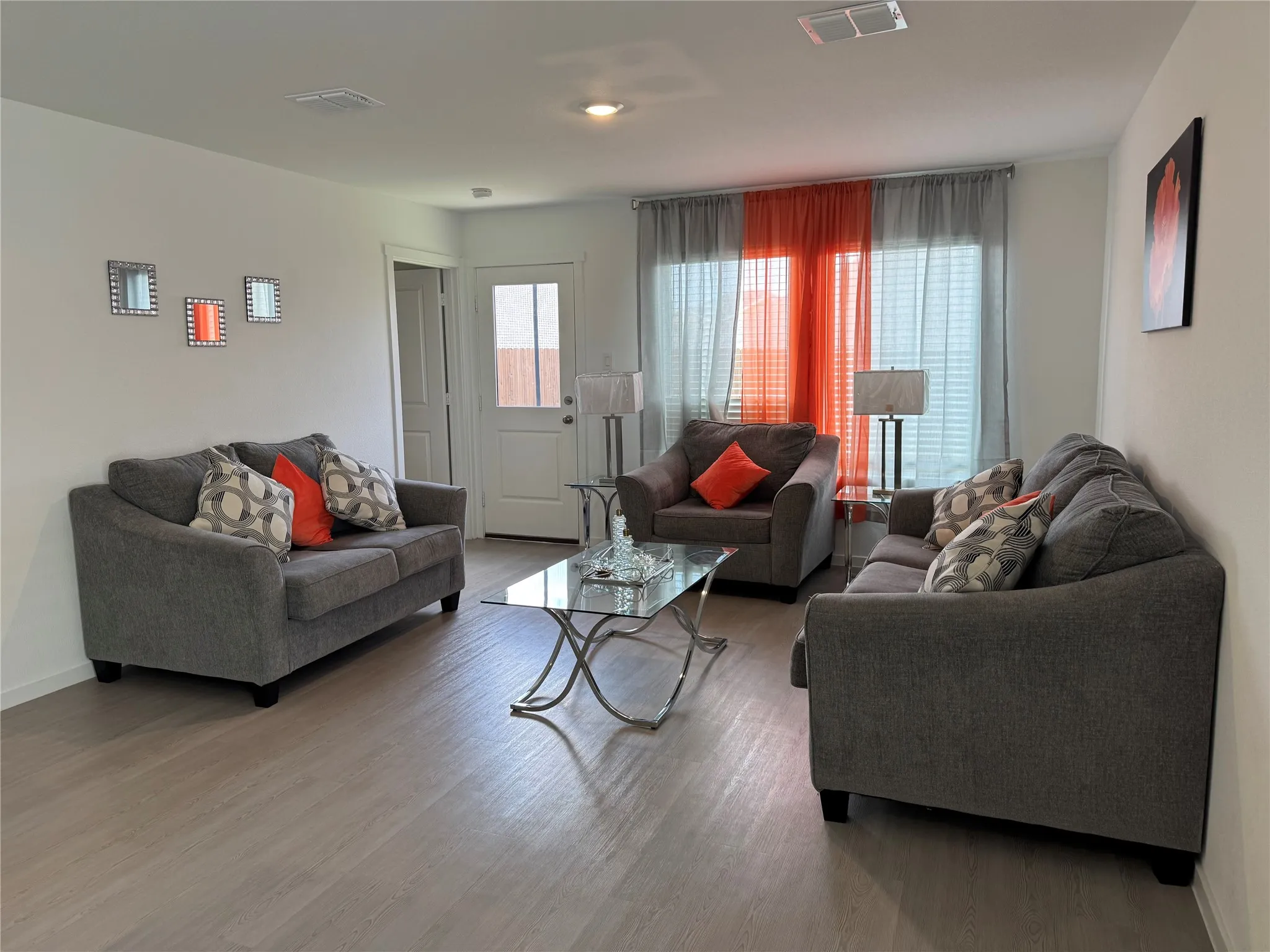 Open-concept living area featuring light wood-finish flooring, recessed lighting, white walls, and a glass-paneled exterior door