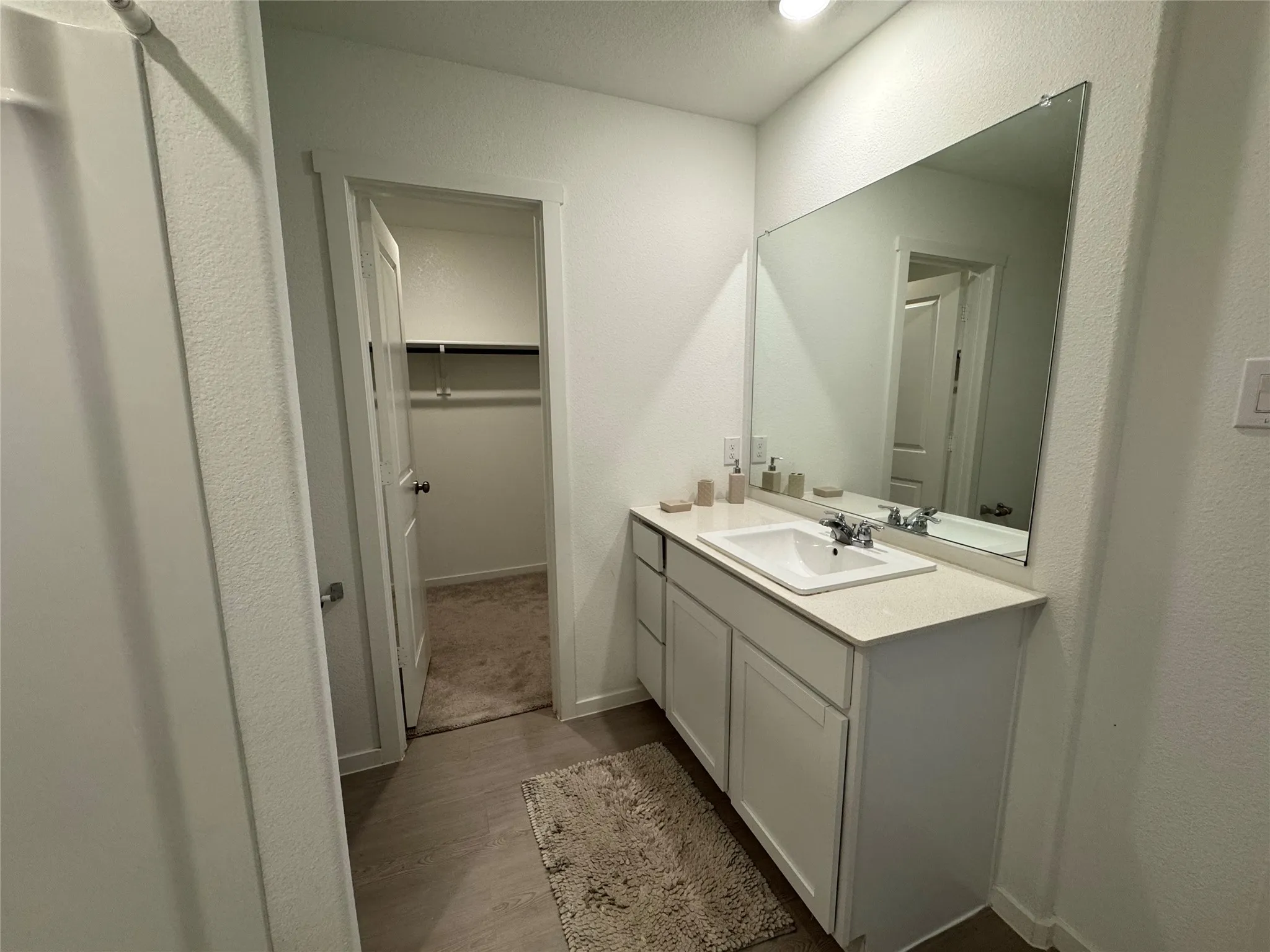 Bathroom vanity with an integrated sink, polished chrome faucet, and expansive mirror