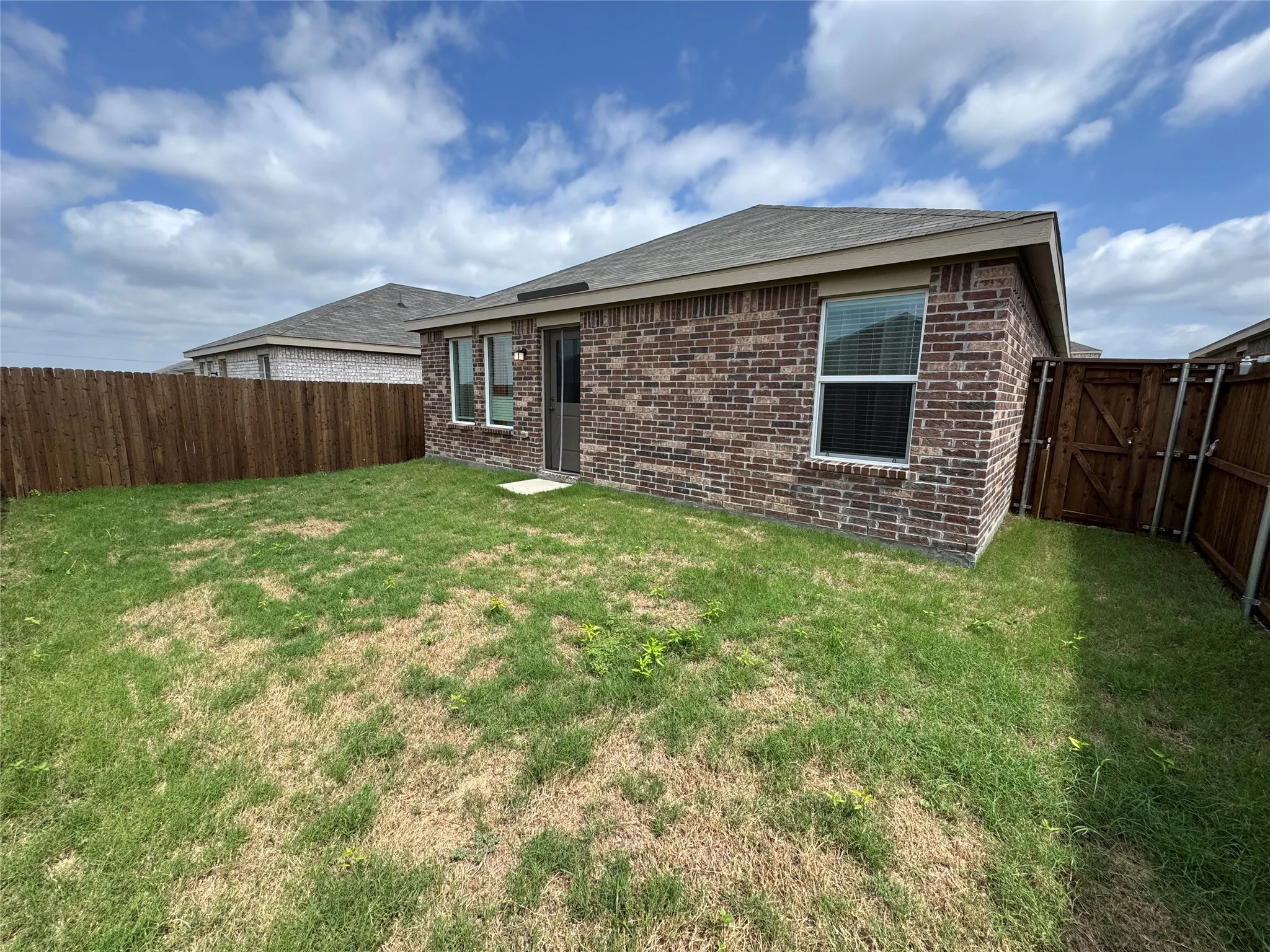 Private backyard featuring a brick exterior, a wood privacy fence, and a side gate