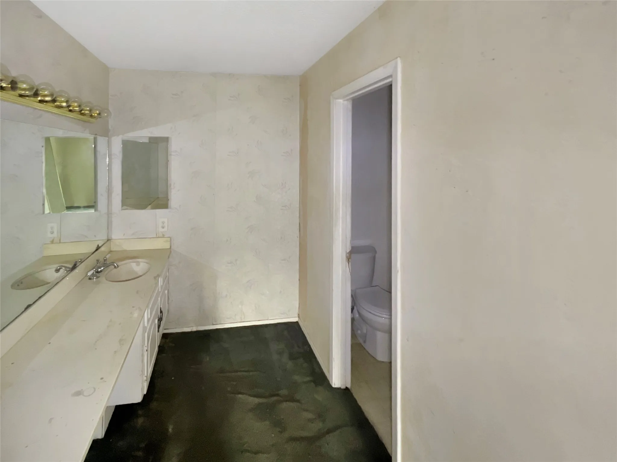 Bathroom featuring a double vanity with integrated sinks, large mirrors, overhead lighting fixture, and a separate water closet