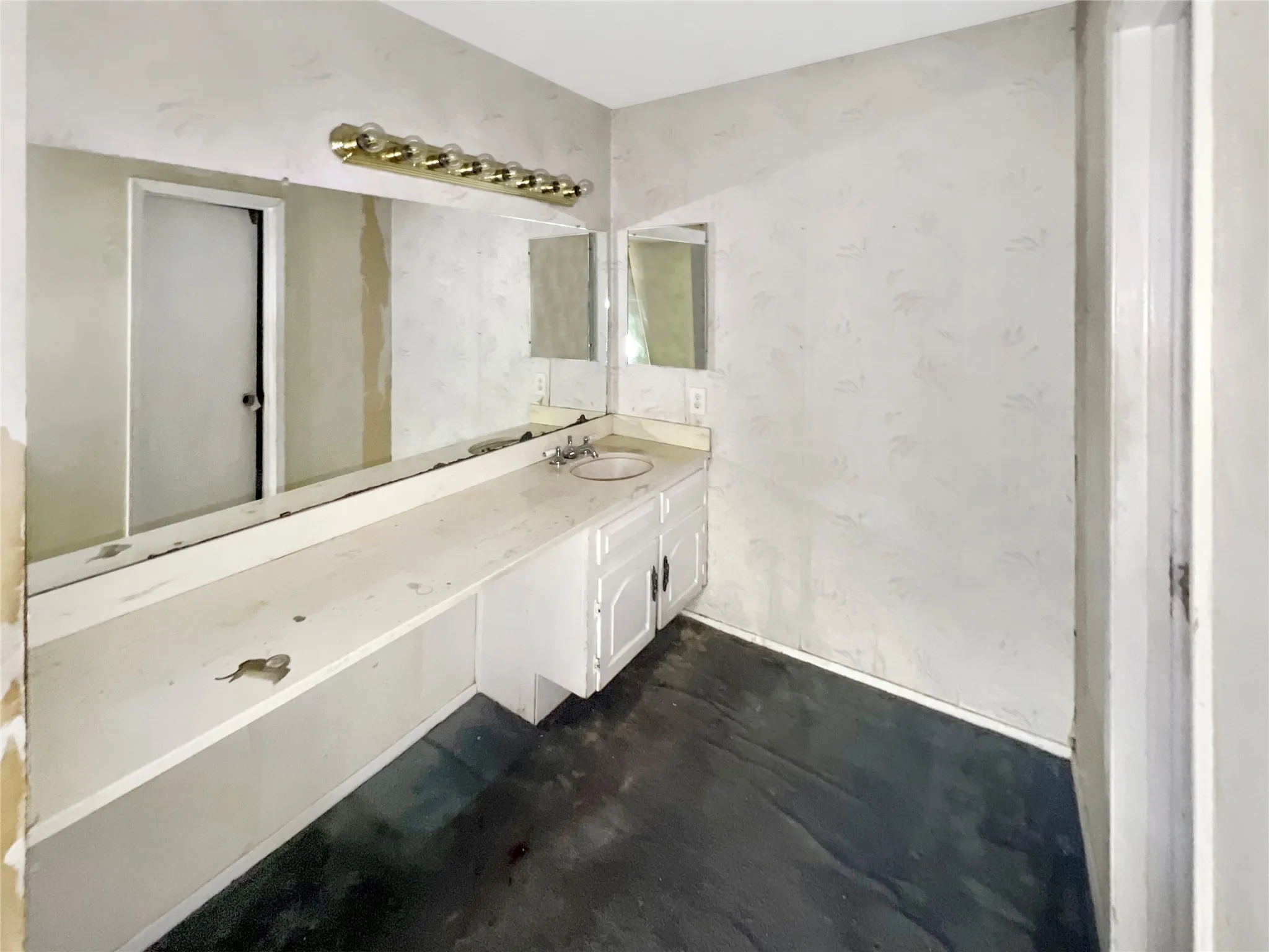 Bathroom featuring a single basin sink, white cabinetry, and extensive vanity counter space