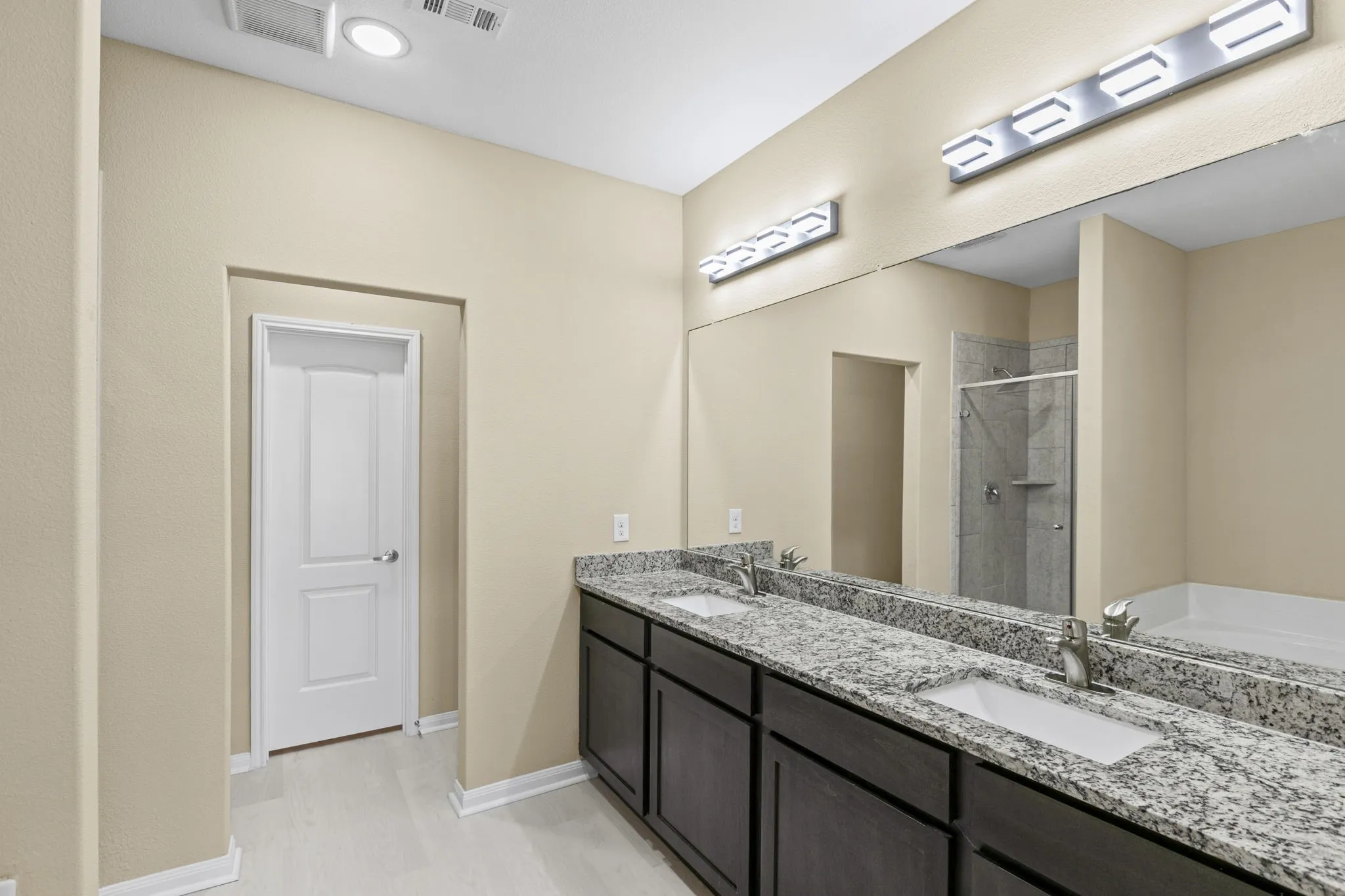 Bathroom featuring a double vanity with granite-finish countertops, dark wood-finish cabinetry, and undermount sinks