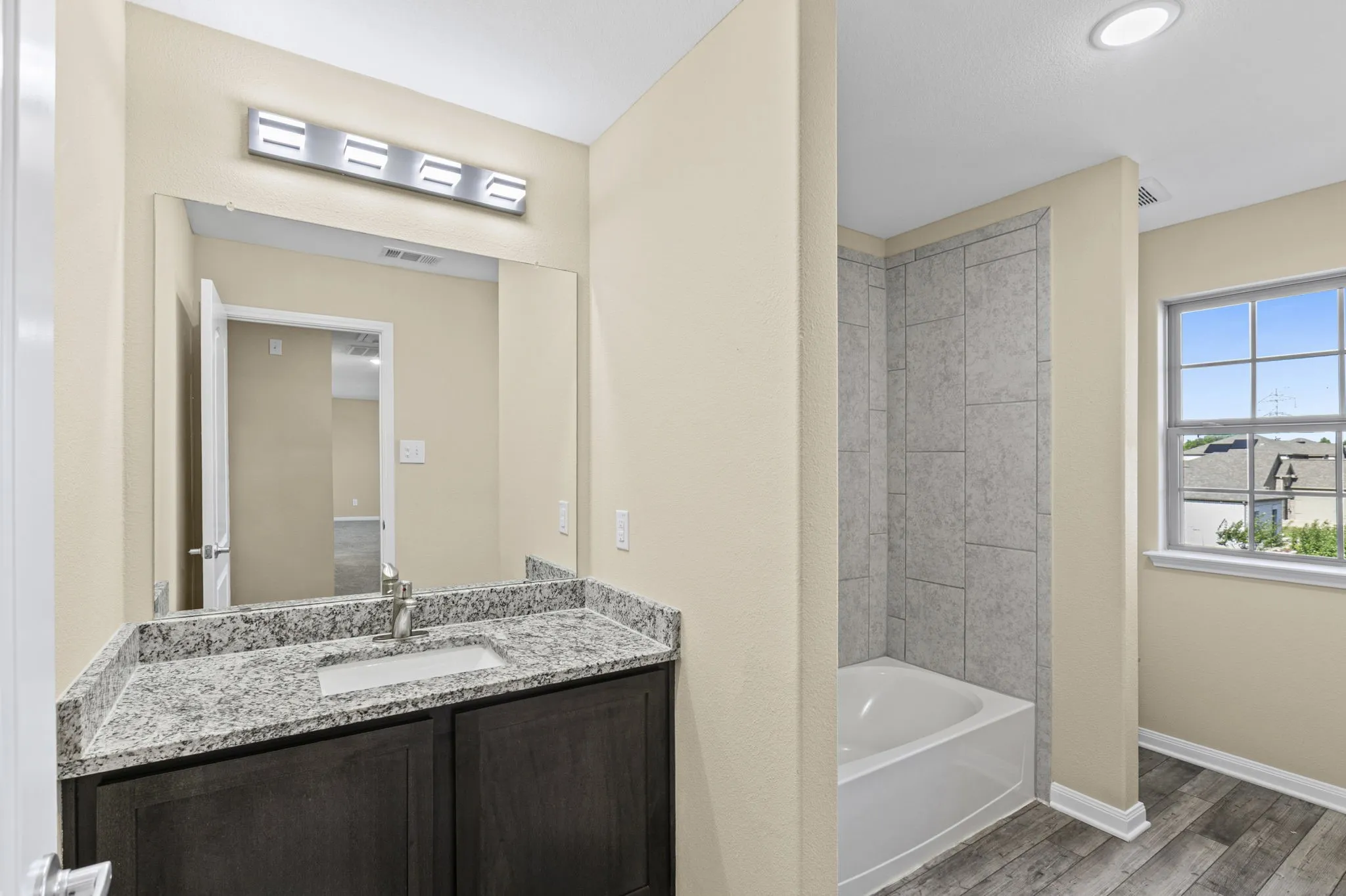Bathroom featuring a dark wood-finish vanity with a light-colored granite countertop and undermount sink