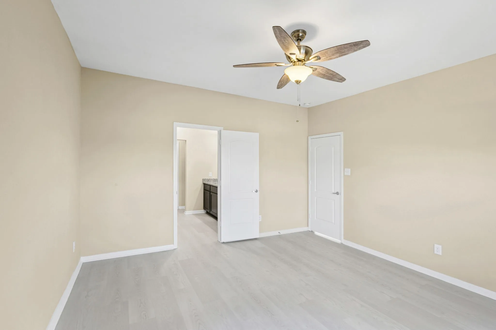 Spacious room featuring vaulted ceilings, light wood-finish flooring, and neutral wall tones