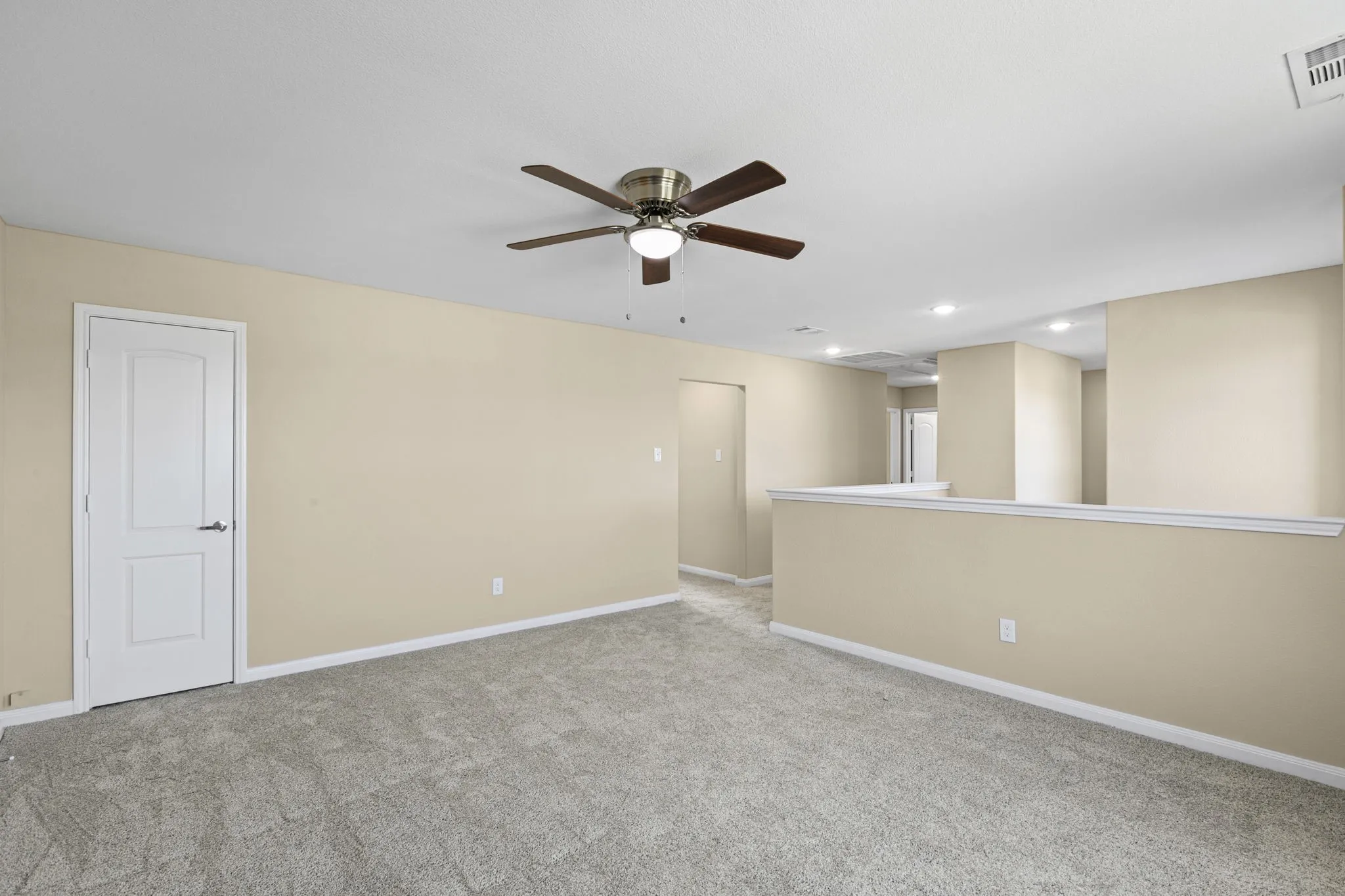 Carpeted room featuring a ceiling fan with integrated lighting, recessed lighting, and a half-wall partition