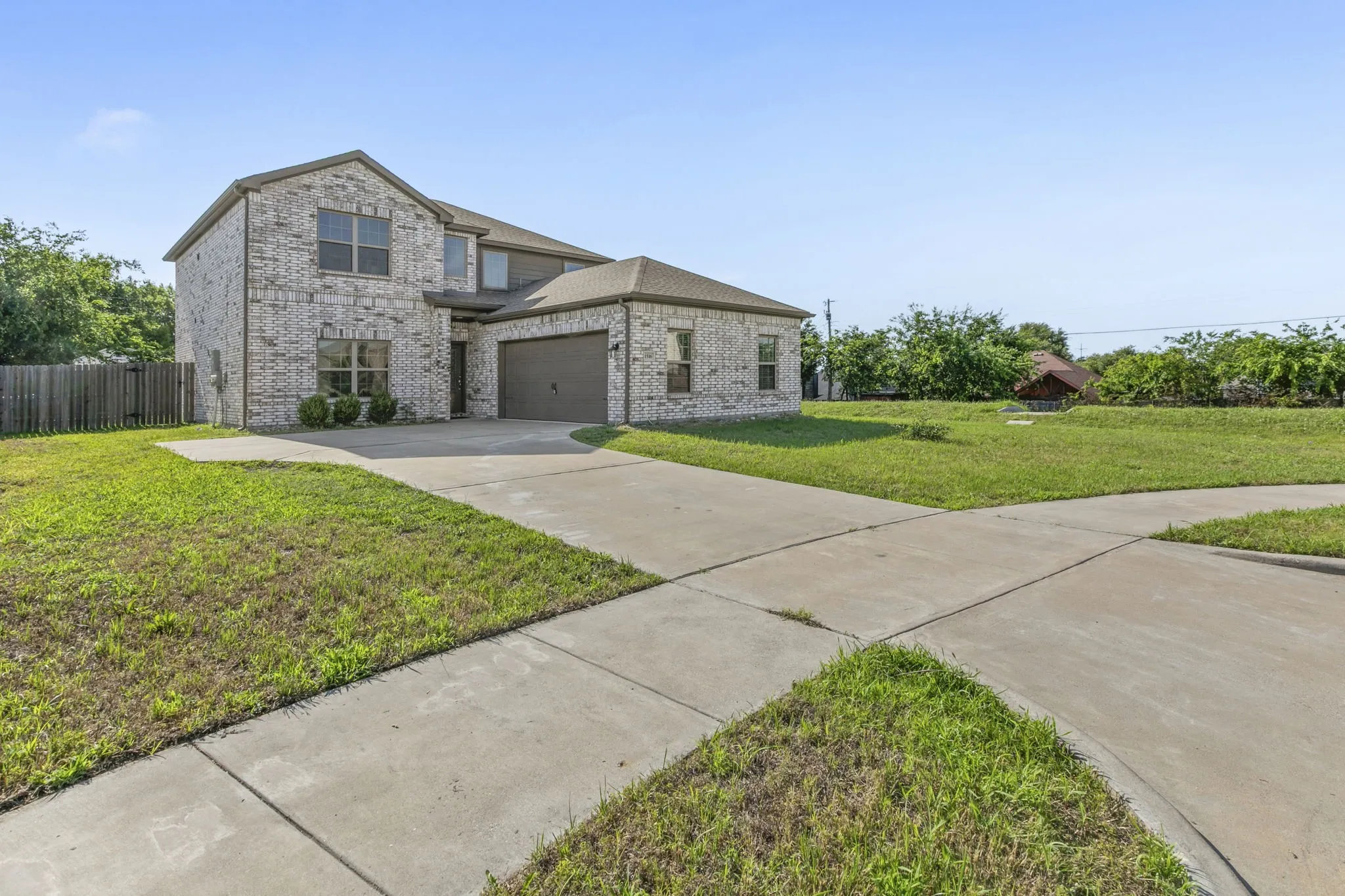 Two-story brick exterior featuring a multi-pane window design, an attached garage, and a concrete driveway