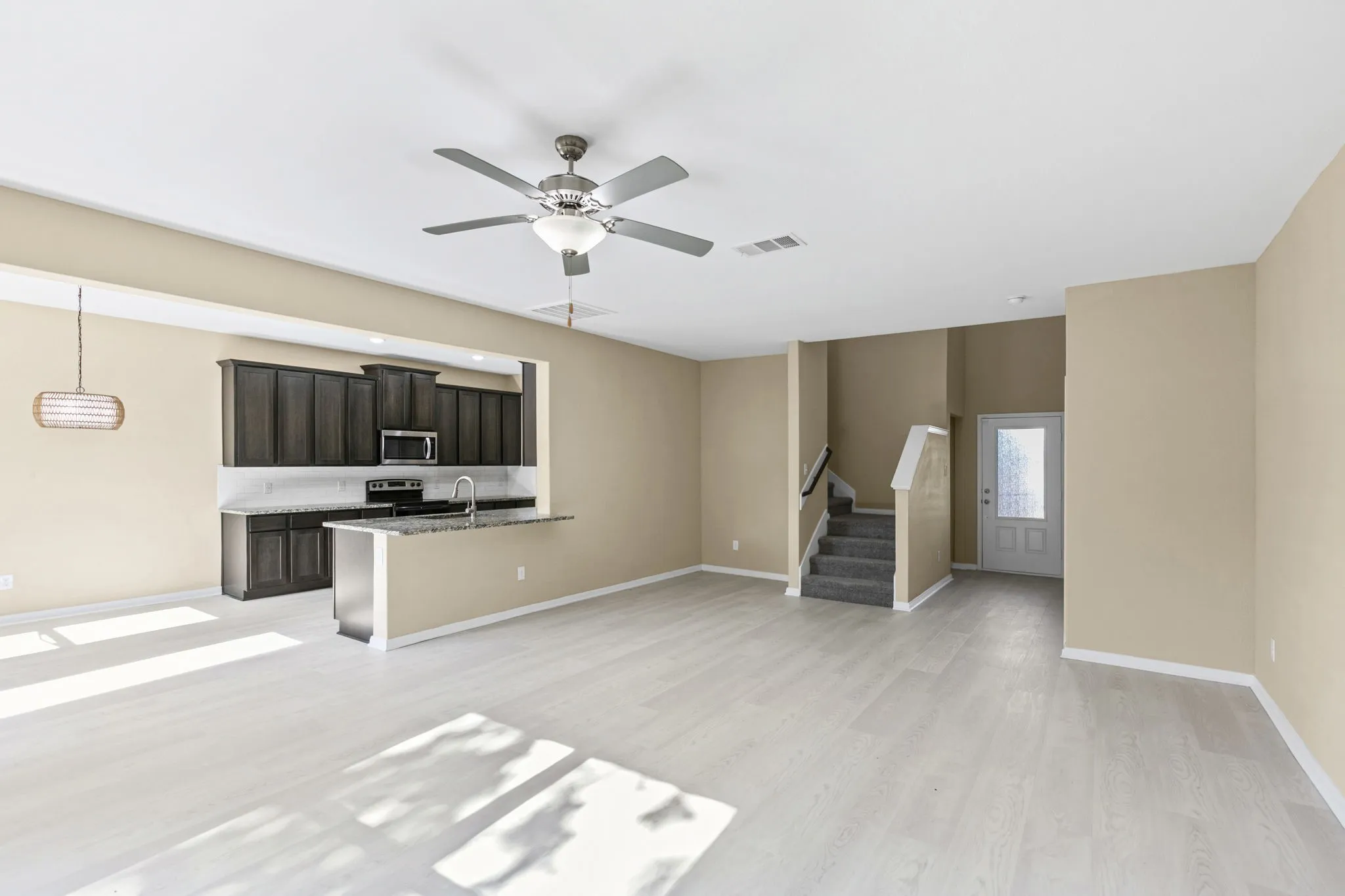 Open-concept living area featuring light wood-finish flooring, a contemporary ceiling fan, and recessed lighting