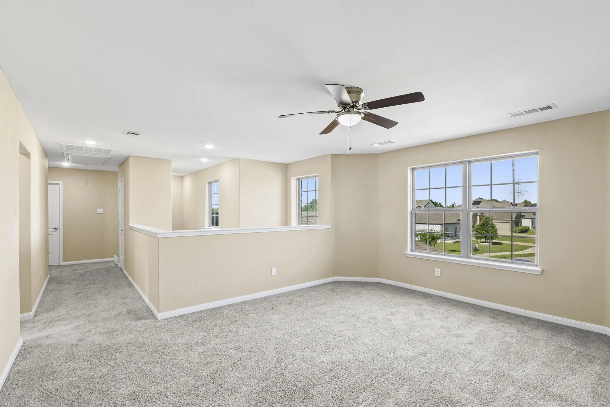 Spacious loft area featuring light gray carpet flooring and neutral wall tones
