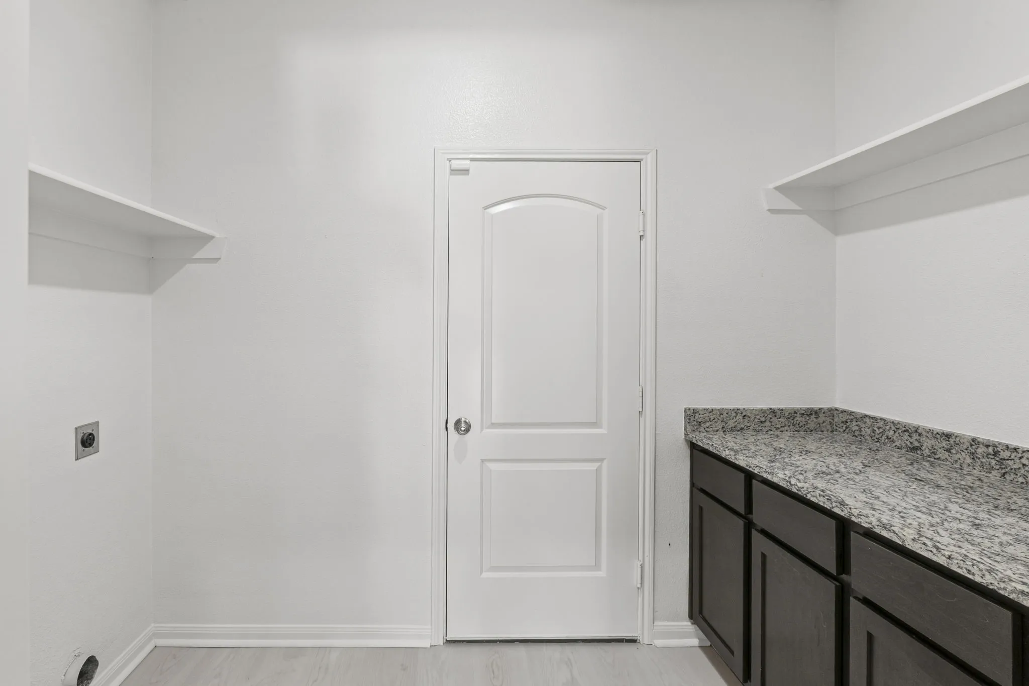Utility space featuring dark wood-finish cabinetry, a speckled countertop, and two built-in storage shelves