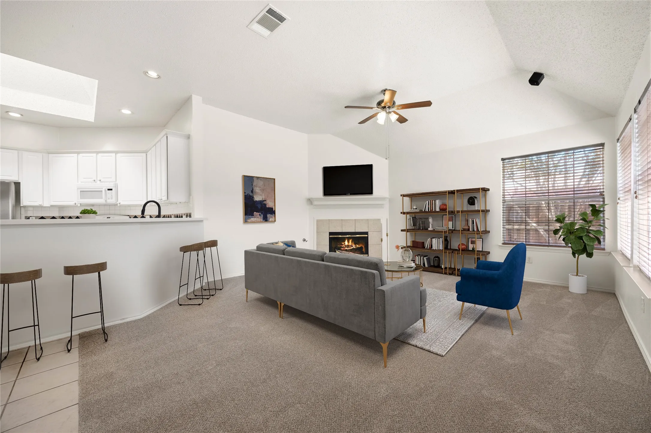 Vaulted great room featuring a fireplace with a tile surround, a breakfast bar, recessed lighting, and a ceiling fan