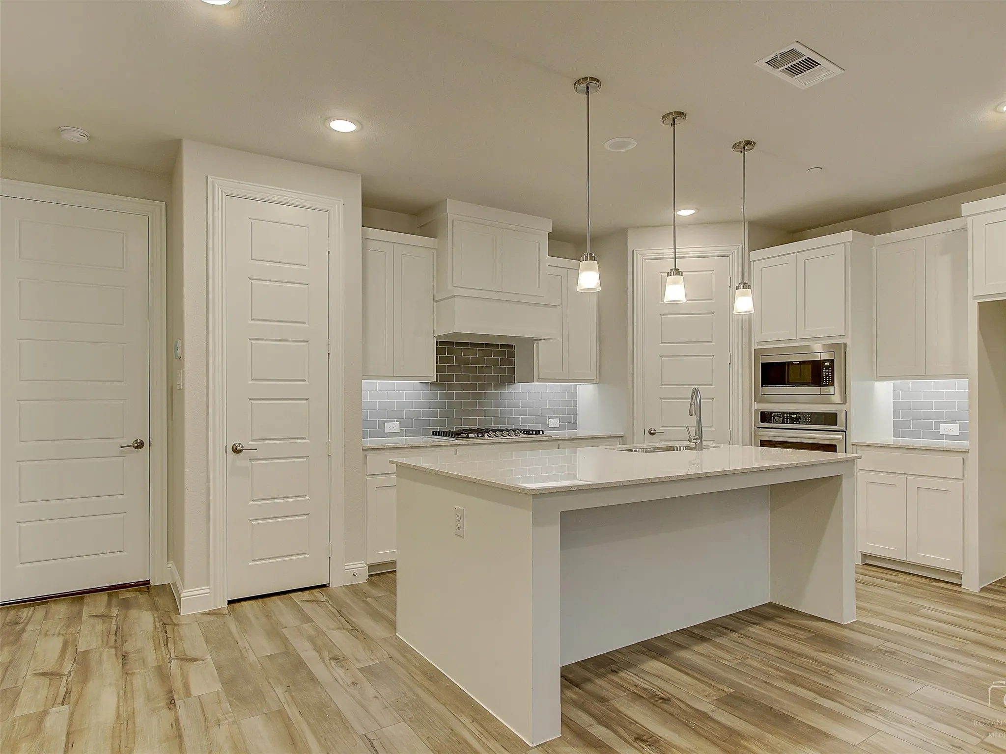 Modern kitchen featuring a central island, recessed lighting, and wood-finish flooring