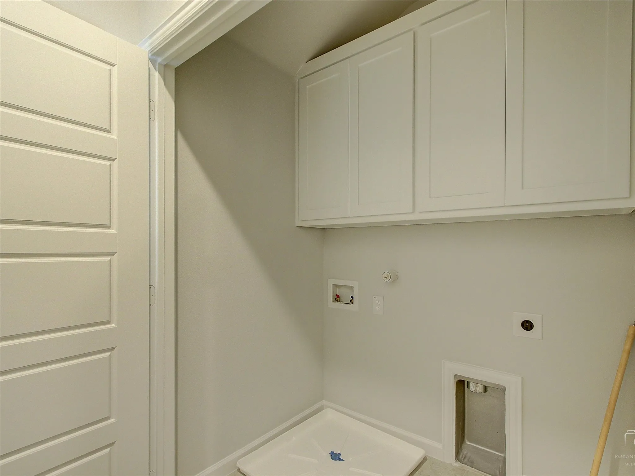 Utility room featuring white cabinetry, light-toned walls, and a paneled door