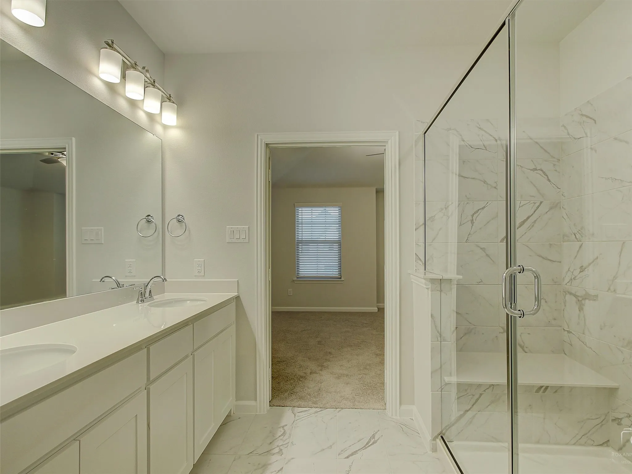 Contemporary bathroom featuring a double vanity with ample storage, a large frameless mirror, and a spacious glass-enclosed shower with a built-in bench