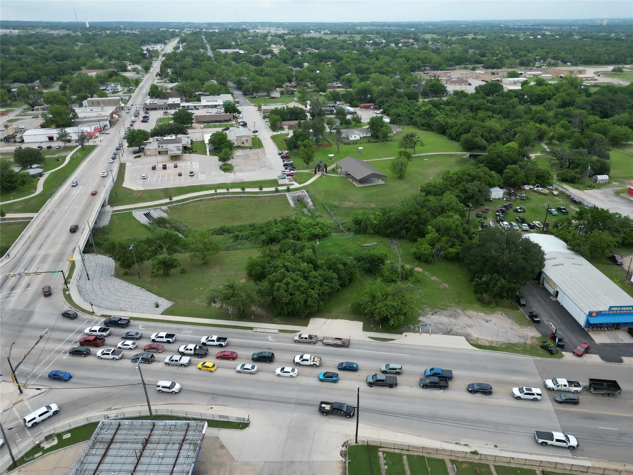 Aerial perspective showcasing a multi-lane roadway and overpass, surrounded by mature trees and commercial structures