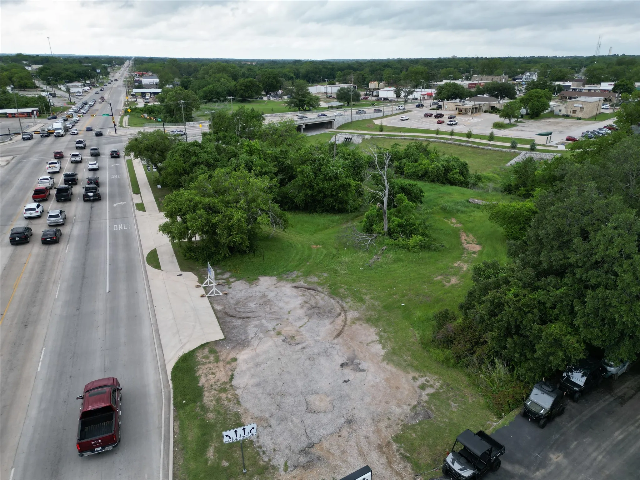 Expansive vacant land parcel featuring partial paved access and surrounding mature trees