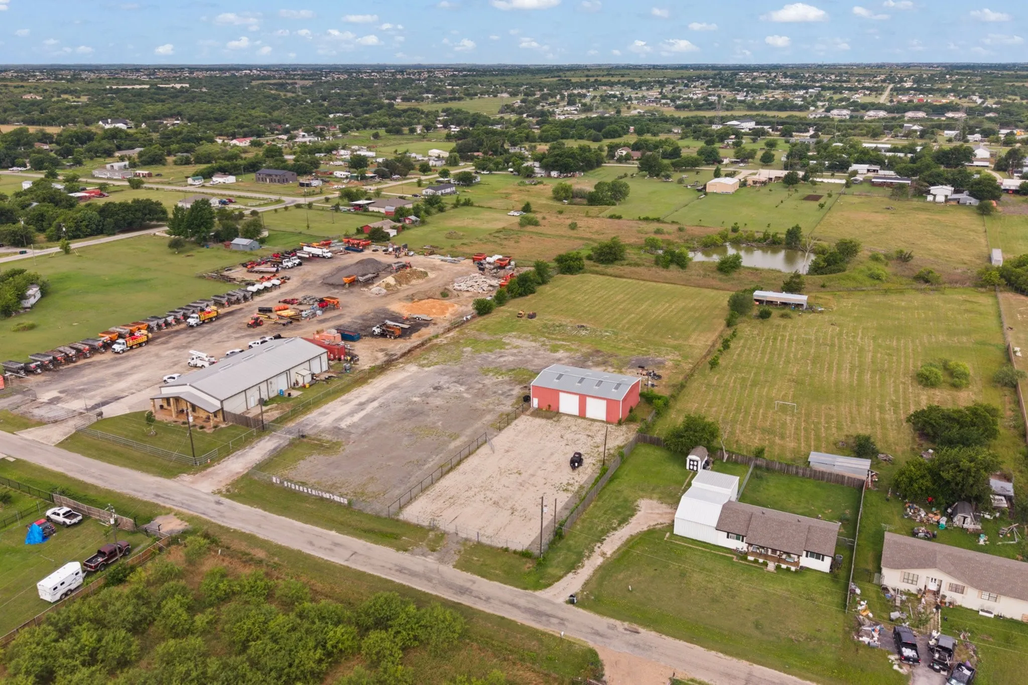 Expansive property featuring a large commercial building with a gray metal roof and brick facade