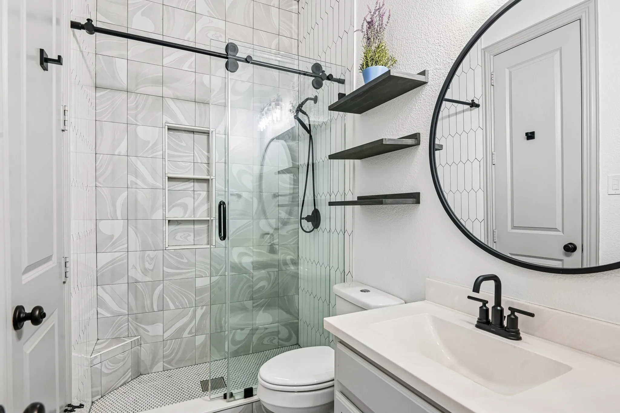 Bathroom featuring a glass-enclosed shower with custom tile, a built-in shower niche, and a tiled shower bench