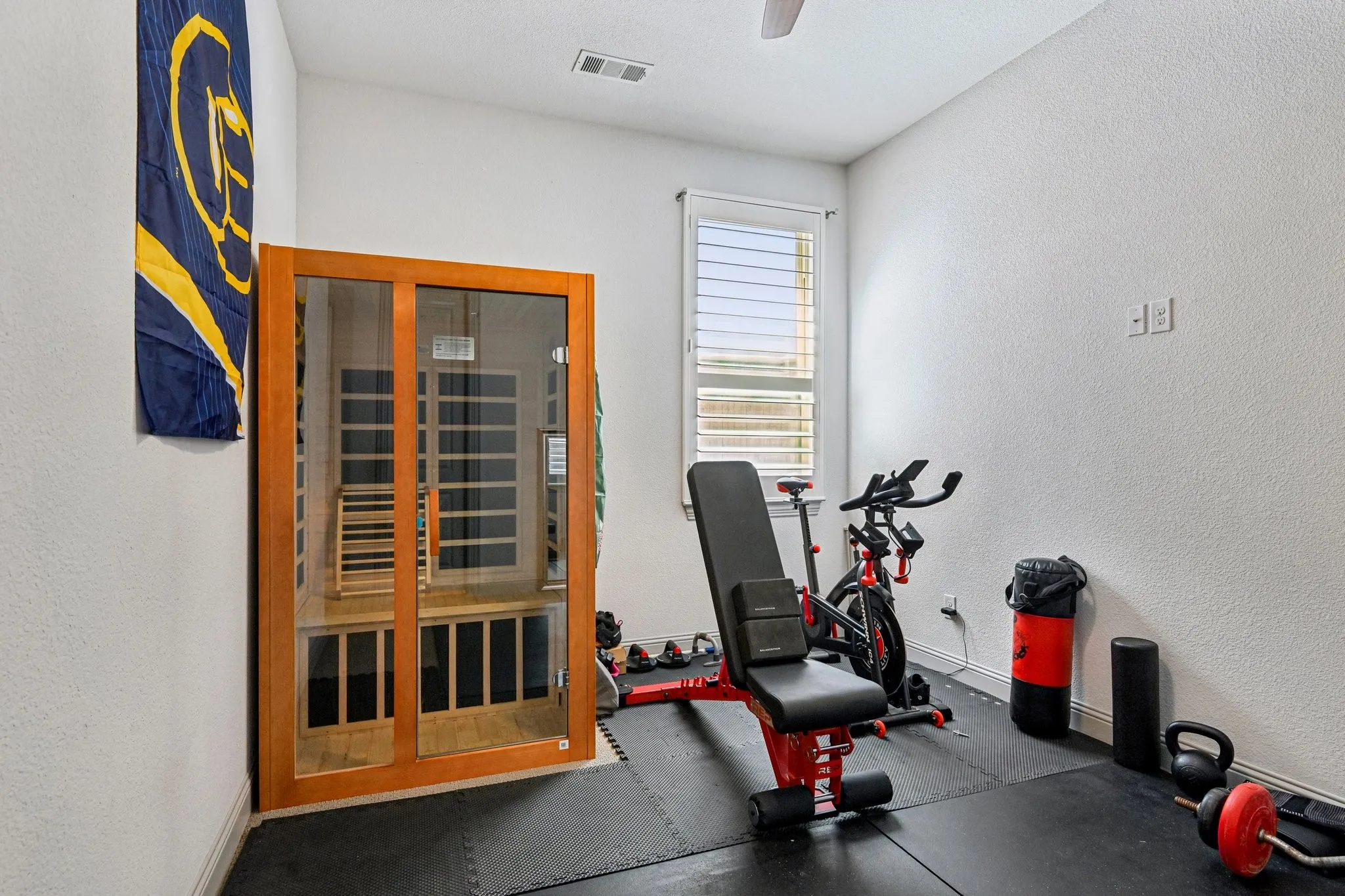 Dedicated room featuring an integrated wood-finish sauna with glass doors, a window with louvered blinds, and a ceiling fan