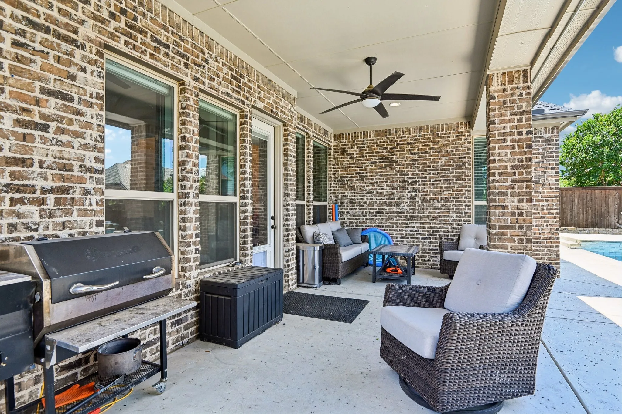 Spacious covered patio with brick exterior and recessed lighting