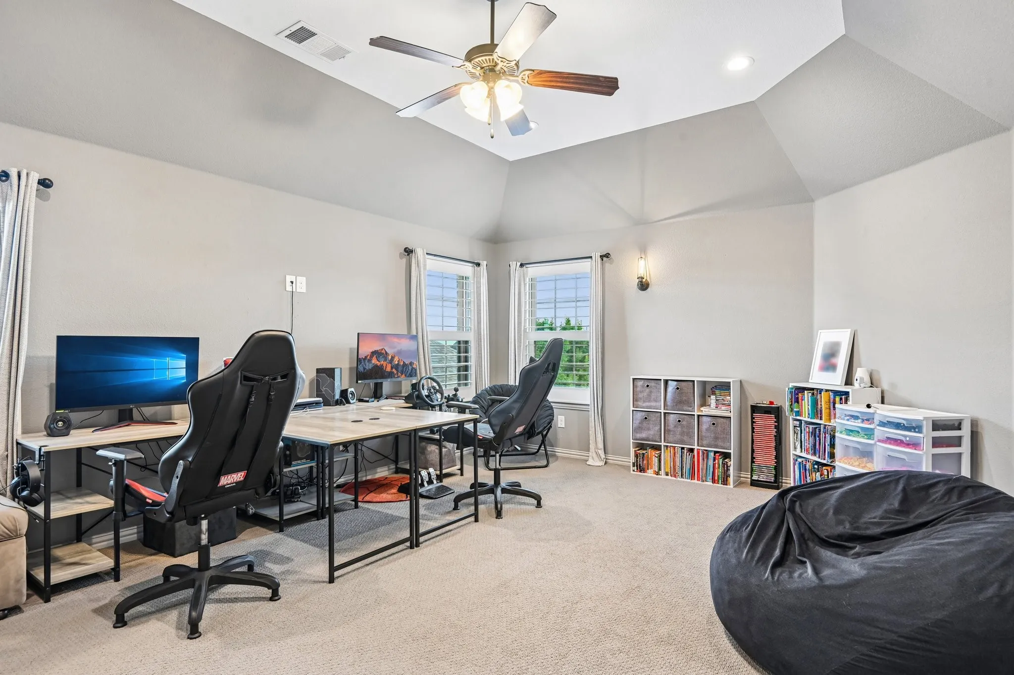 Carpeted room featuring a vaulted ceiling with a central ceiling fan