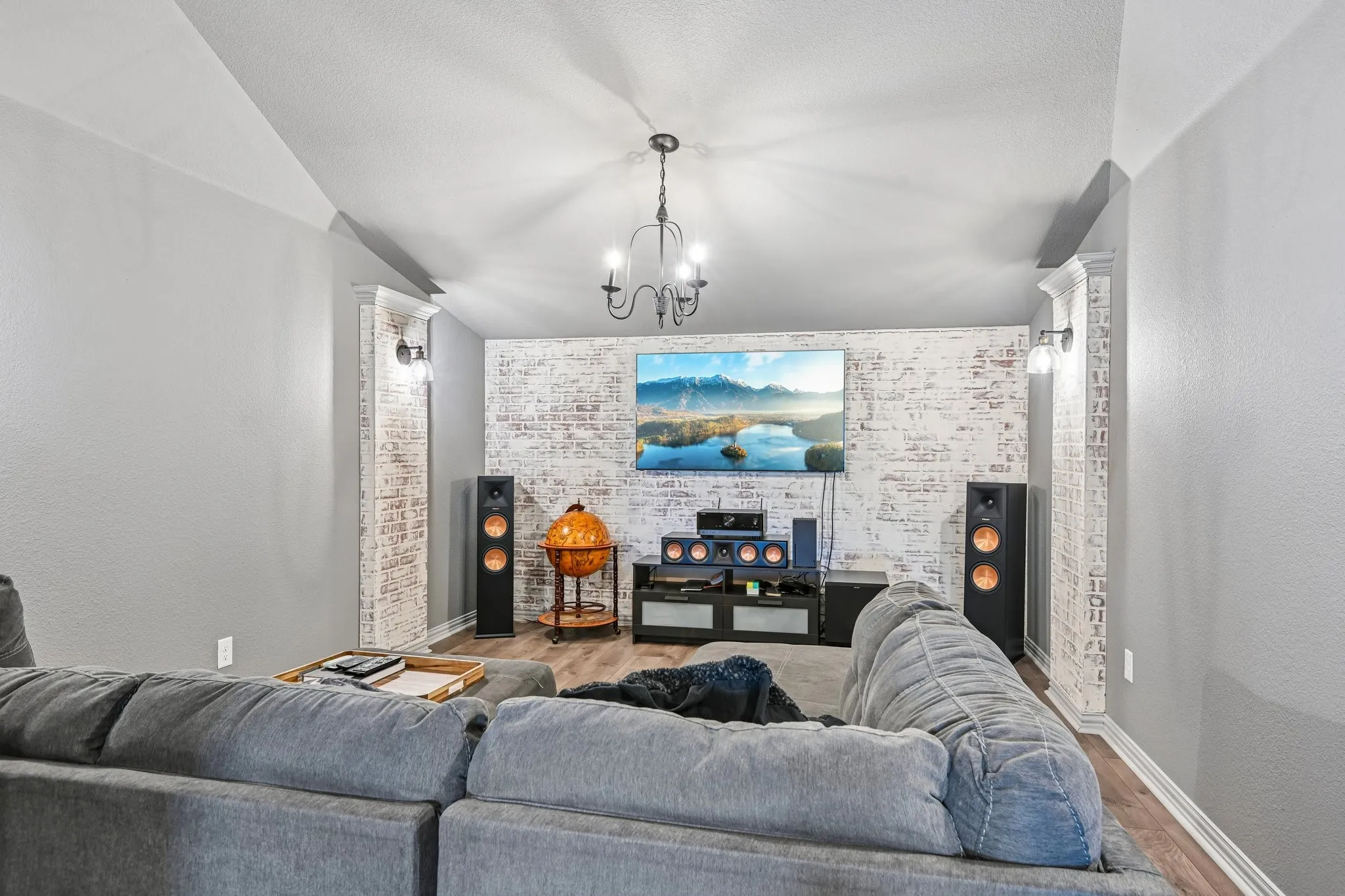 Living area featuring a textured accent wall, wood-finish flooring, and crown molding