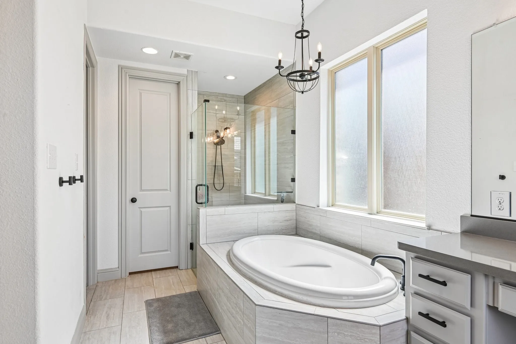 Spa-inspired bath featuring a built-in soaking tub with surrounding tile, a walk-in shower with glass enclosure, and a vanity with integrated drawers