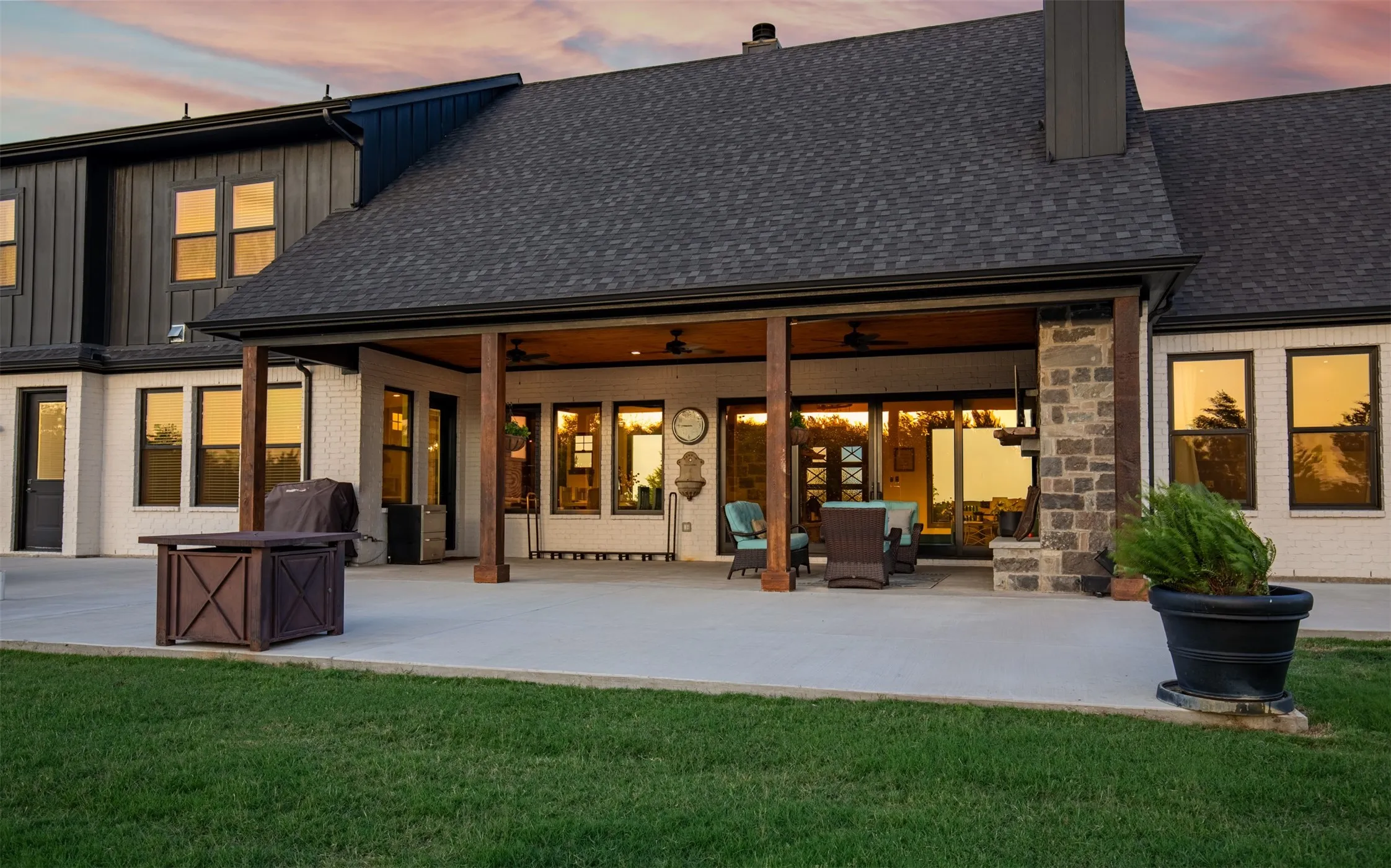 Expansive covered patio featuring a concrete slab, wood-finished support beams, and ceiling fans