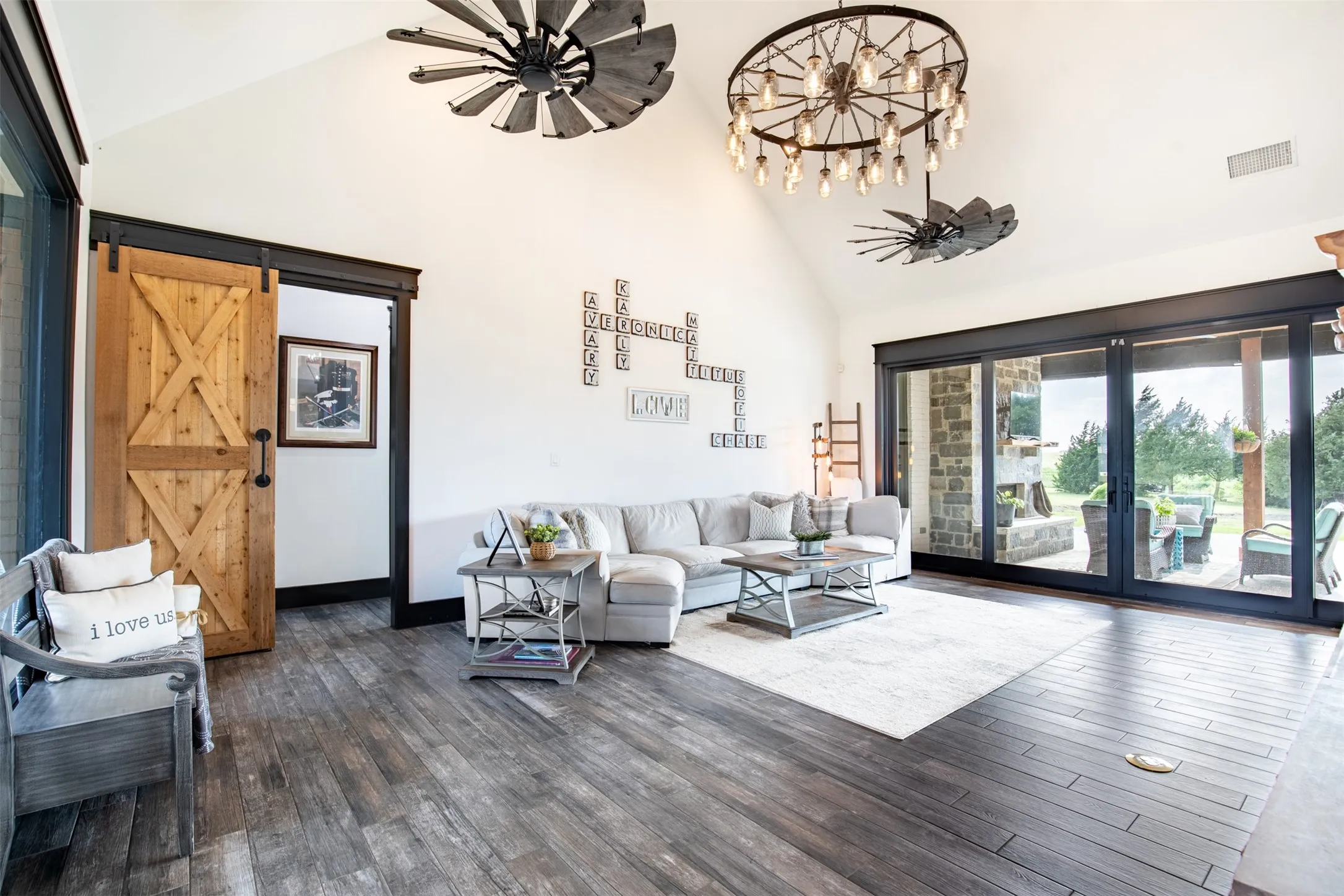 Spacious living area featuring vaulted ceilings, wood-finish flooring, and a large multi-panel glass slider opening to covered patio
