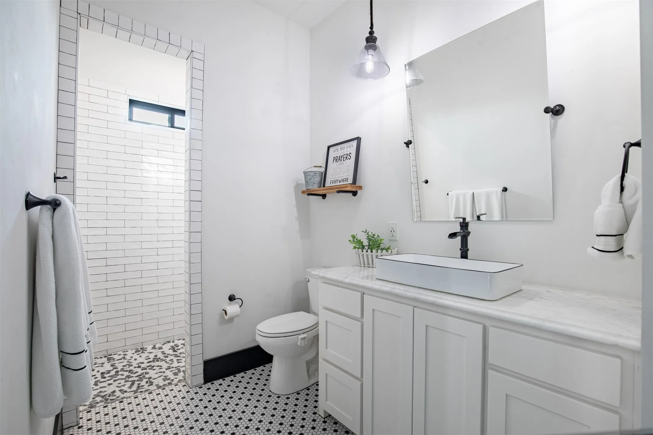 Charming downstairs guest bathroom with white cabinetry, stylized elevated rectangle sink and walk-in shower with privacy